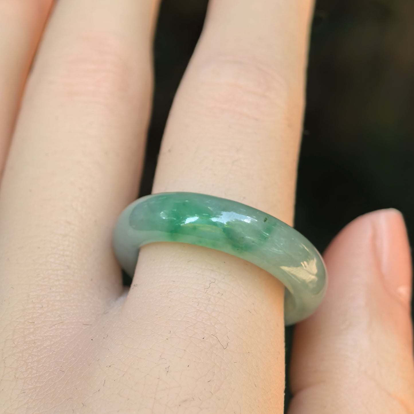 Side wearing view of a light green Burmese jadeite ring band showing its smooth rounded profile and glossy luster.
