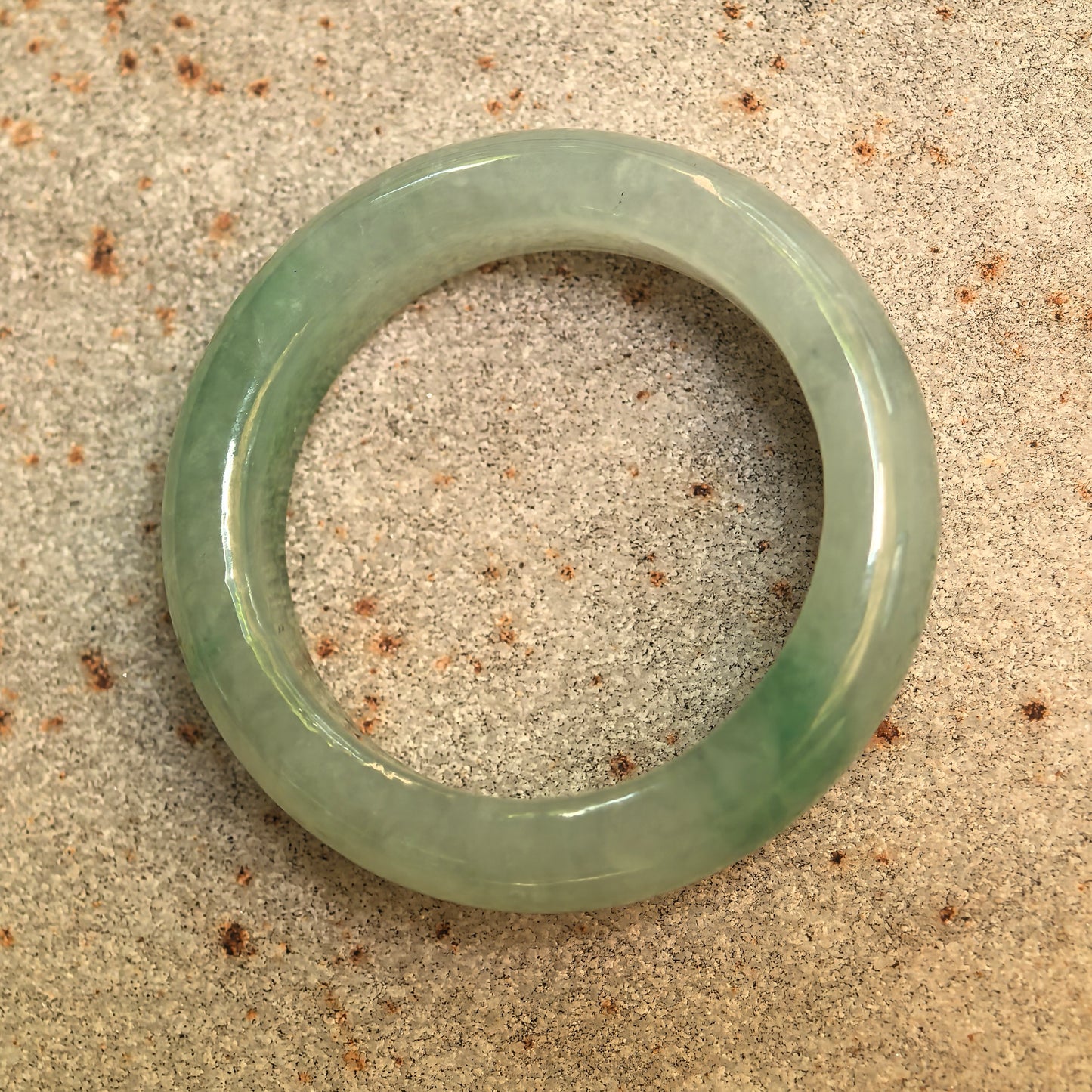 Top view of a round light green Grade-A jadeite ring band showing its polished inner and outer surfaces.