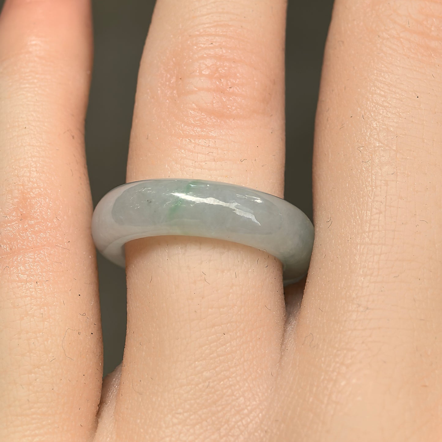 Close-up wearing view of a light green Burmese jadeite ring band with smooth luster and natural green accents.
