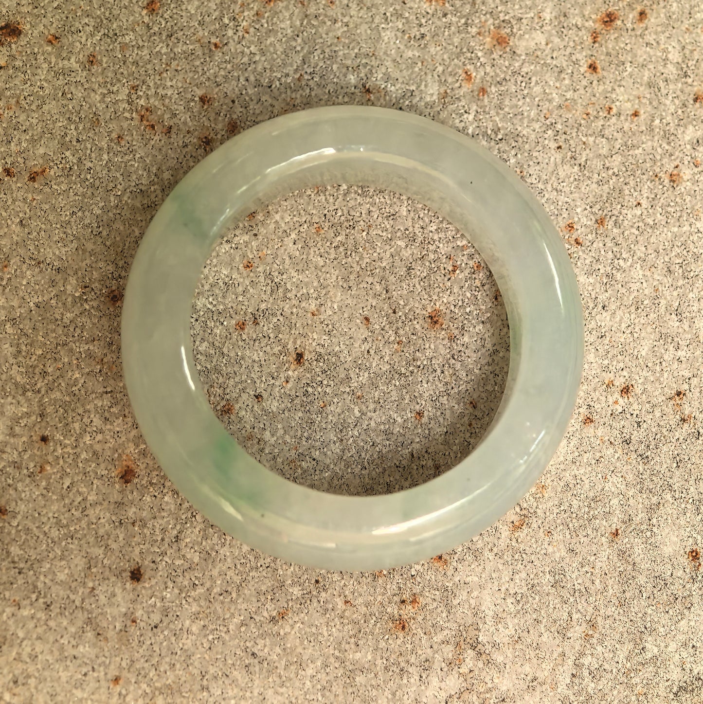 Top view of an icy glutinous light green jadeite ring band showing the circular opening and polished finish.