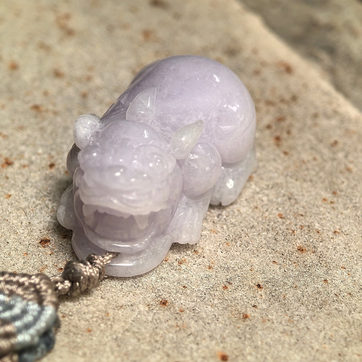 Close-up of a pale lavender Pixiu jadeite pendant showing its rounded three-dimensional carving and polished luster.