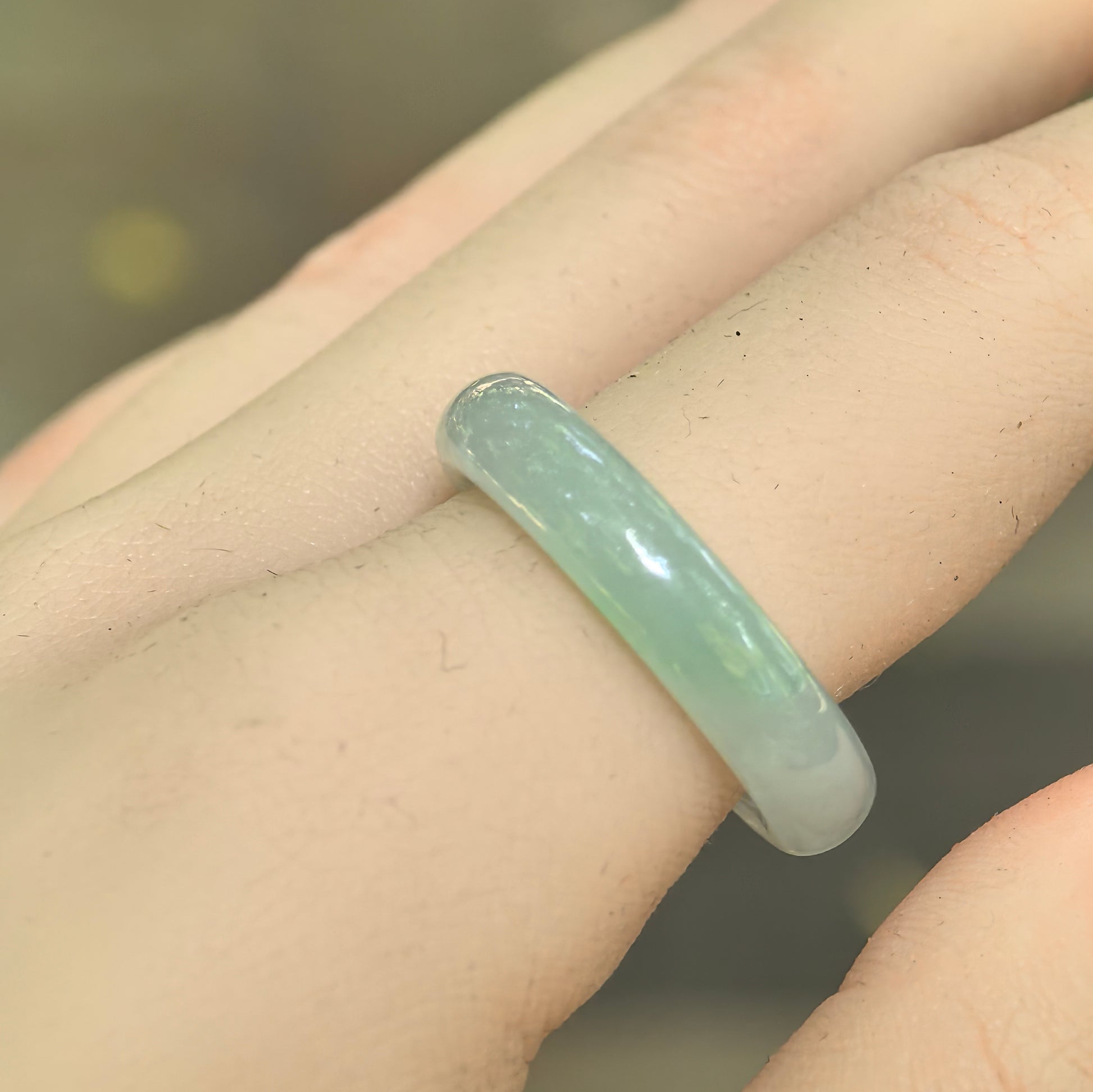 Natural Grade-A icy glutinous light green jadeite ring band worn on the finger, showing its slim round profile.