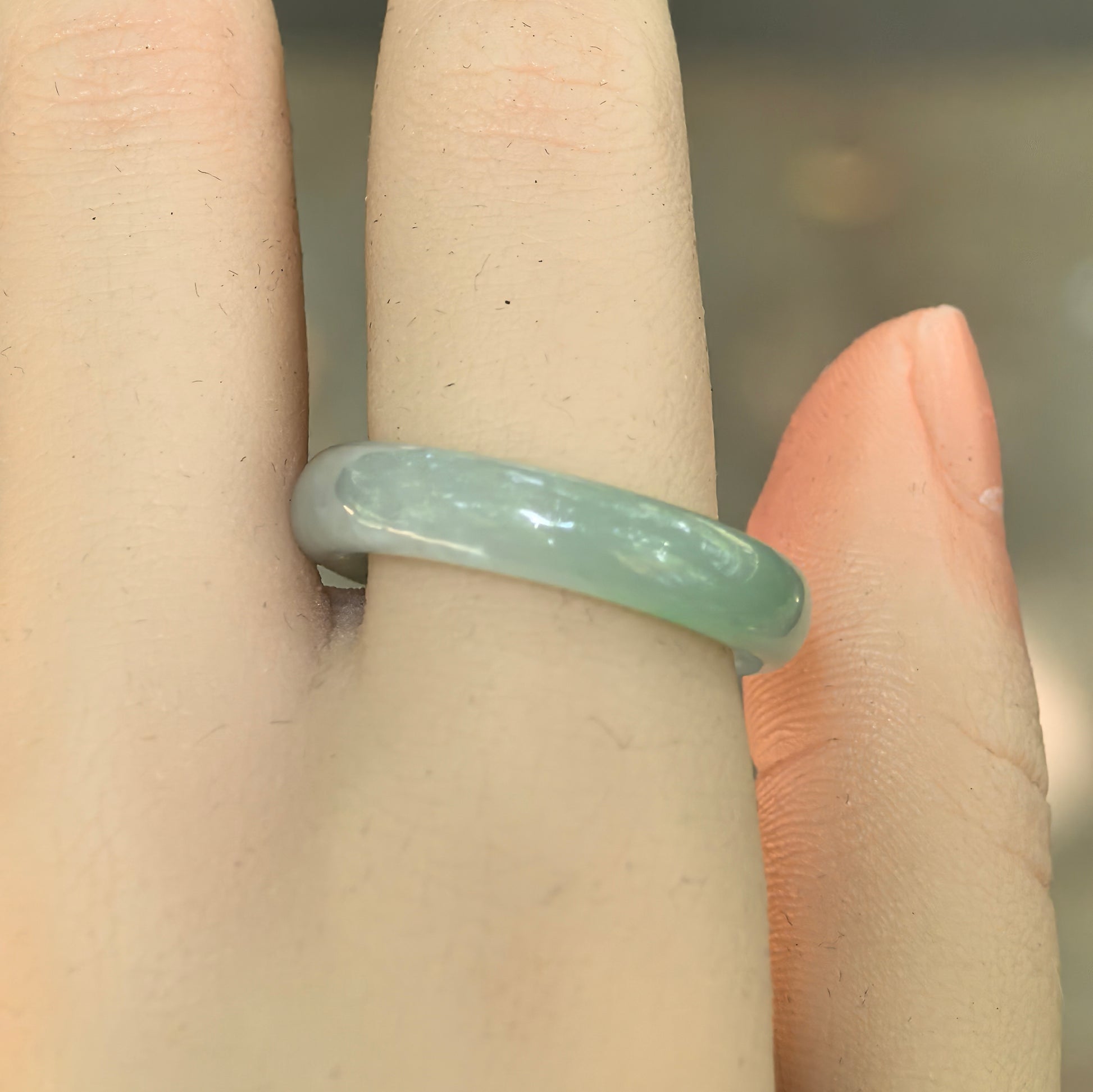 Side view of the light green jadeite ring band showing its smooth polish and gentle translucency.