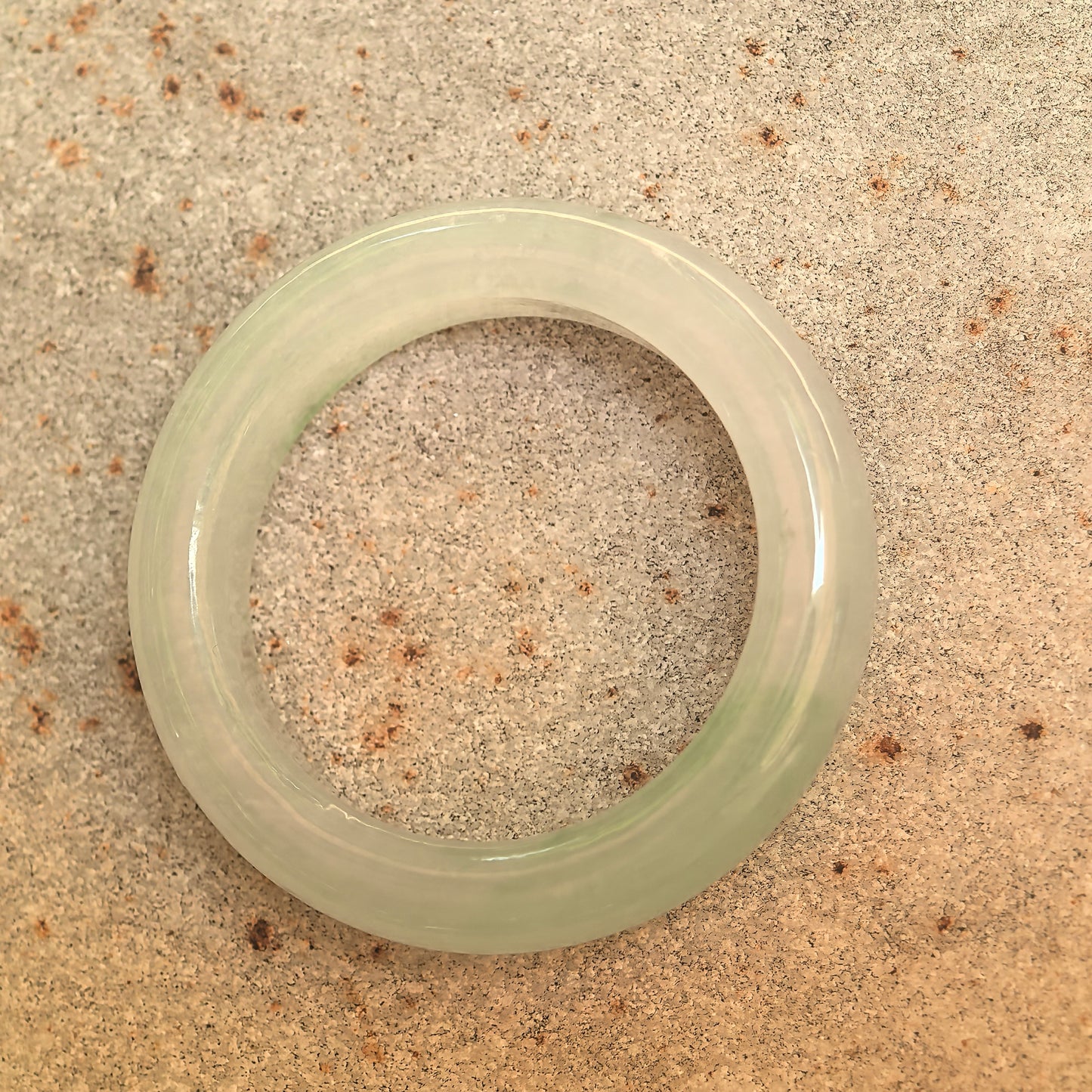 Top view of the icy glutinous light green jadeite ring band showing its inner opening and polished surface.