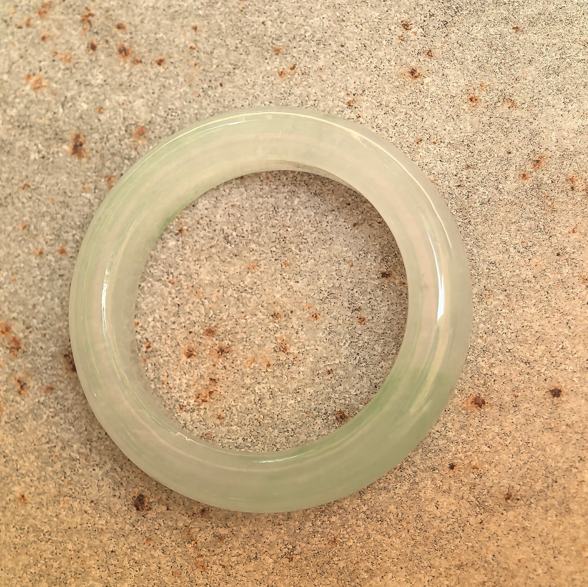 Top view of the icy glutinous light green jadeite ring band showing its inner opening and polished surface.
