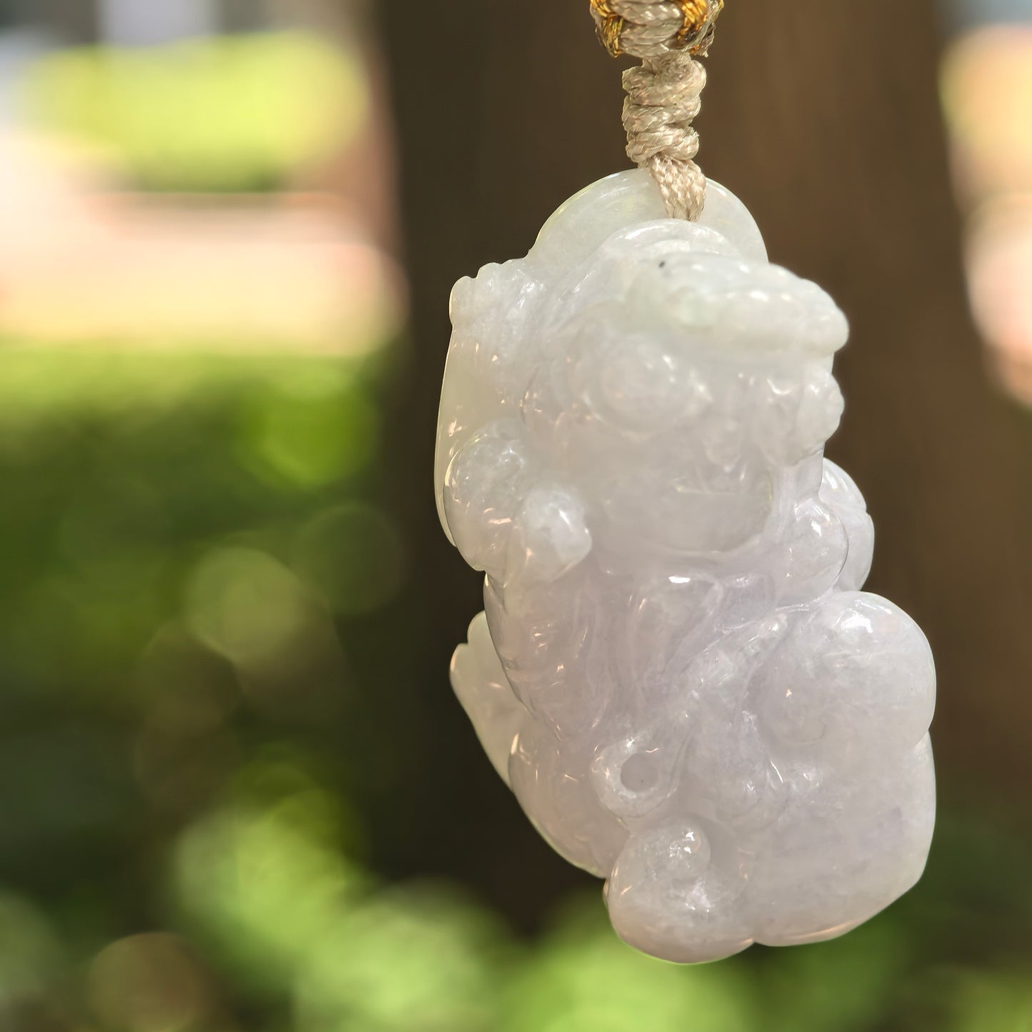 Natural Grade-A glutinous pale lavender Pixiu jadeite pendant hanging from its woven cord.