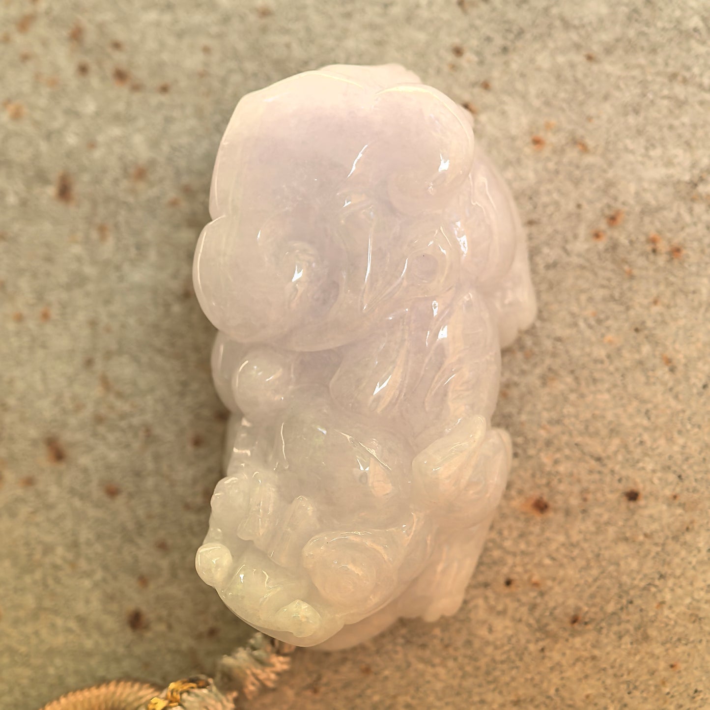 Side view of the glutinous pale lavender Pixiu jadeite pendant showing its thick rounded structure.