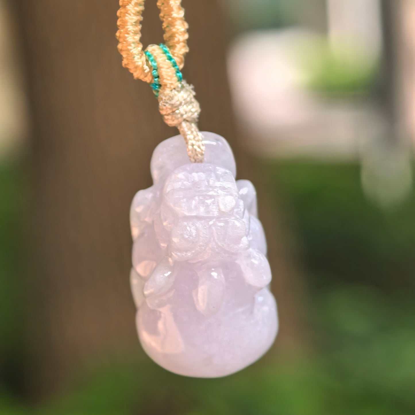 Natural Grade-A glutinous pale lavender Pixiu jadeite pendant hanging from its cord, showing the three-dimensional carved form.