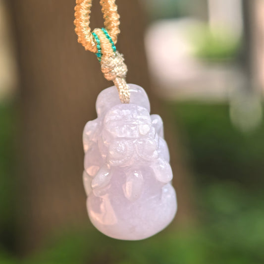 Natural Grade-A glutinous pale lavender Pixiu jadeite pendant hanging from its cord, showing the three-dimensional carved form.