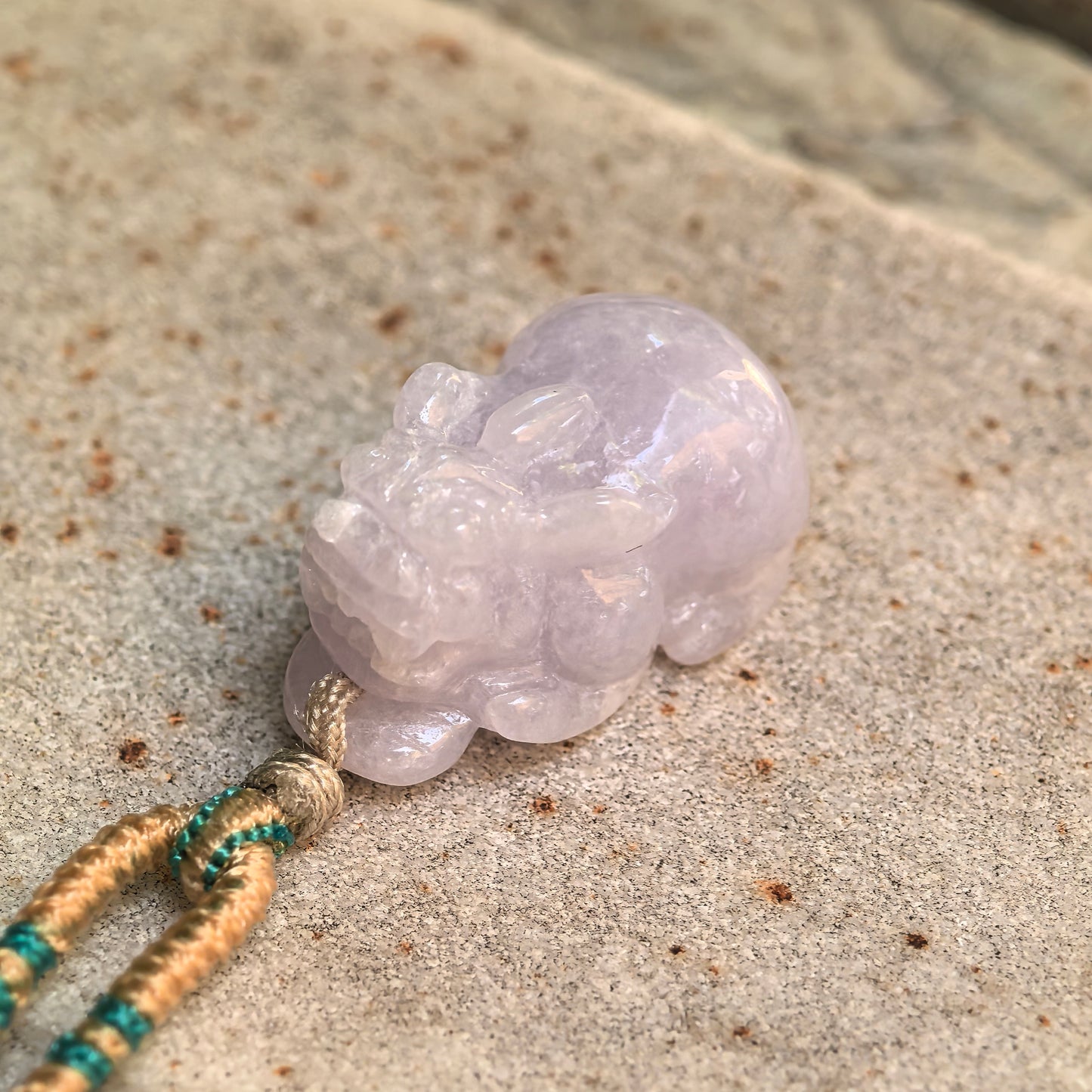 Close-up of the glutinous pale lavender jadeite Pixiu pendant showing detailed facial carving and polished luster.

