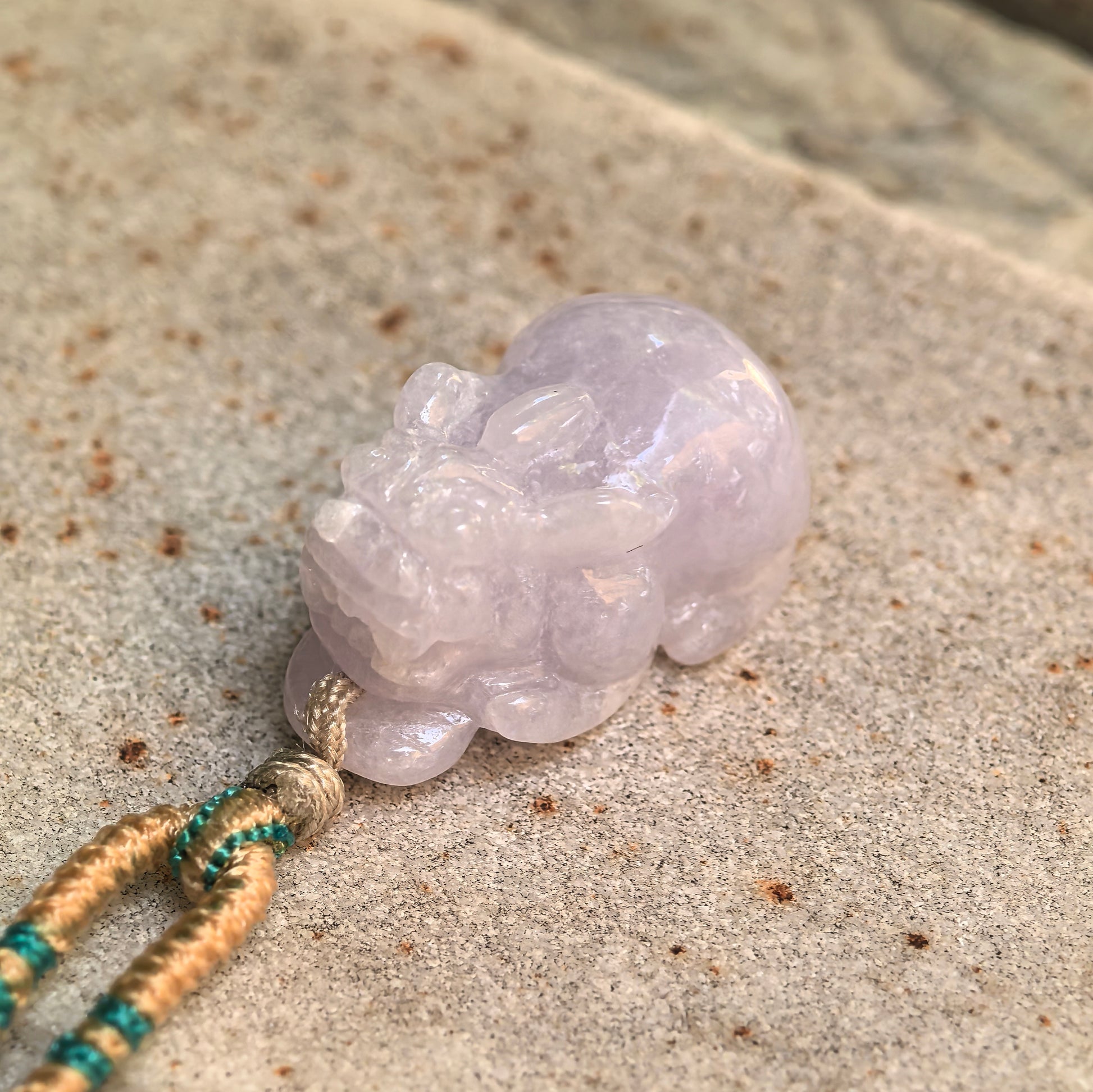 Close-up of the glutinous pale lavender jadeite Pixiu pendant showing detailed facial carving and polished luster.

