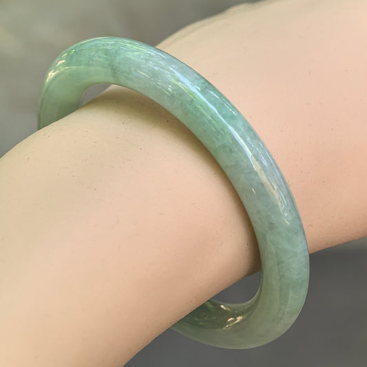 Natural Grade-A icy glutinous mint green jadeite round bangle worn on the wrist, showing its smooth polished profile.