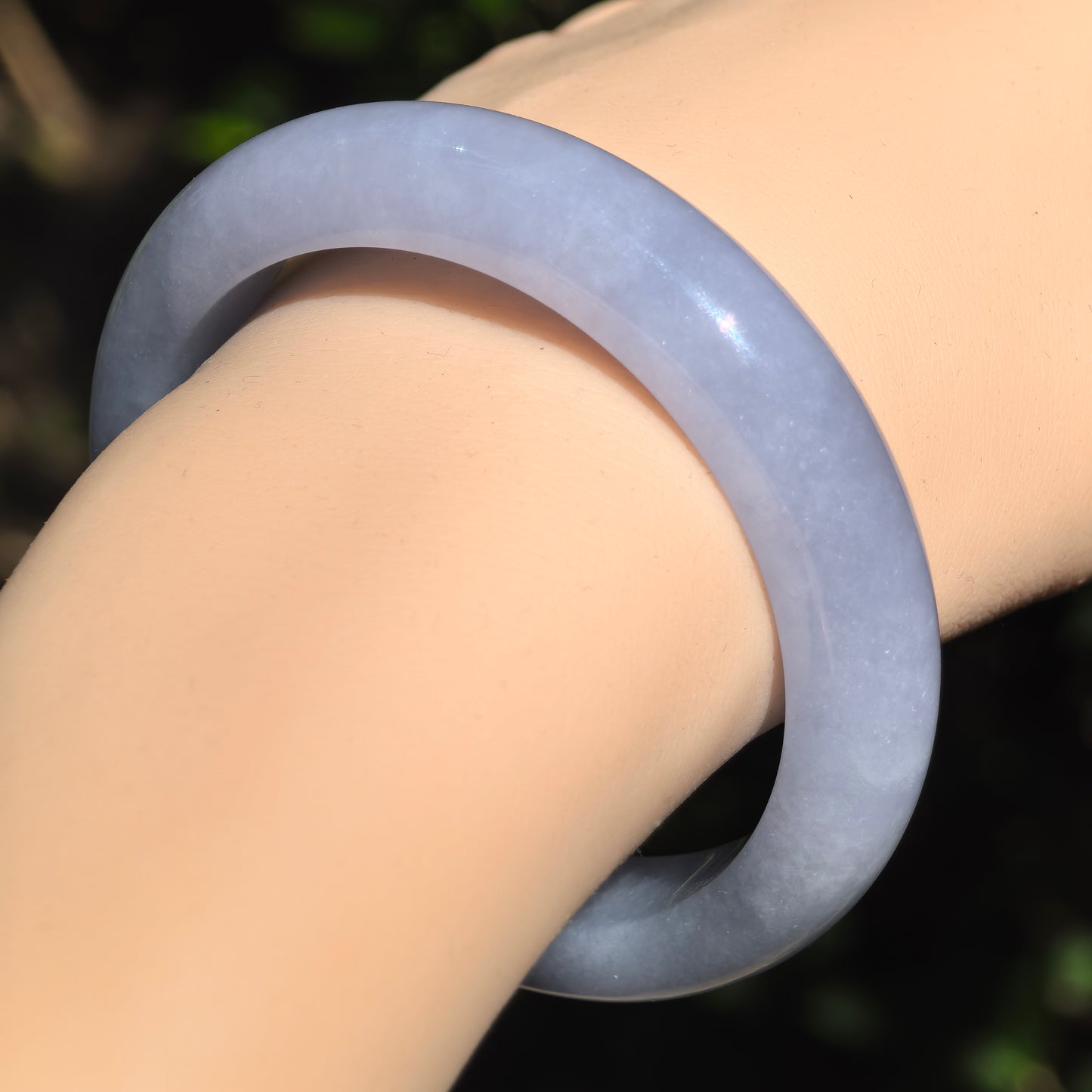 Close-up of glutinous lavender-blue jadeite D-shape bangle worn in natural light, showing subtle color variation and smooth finish.