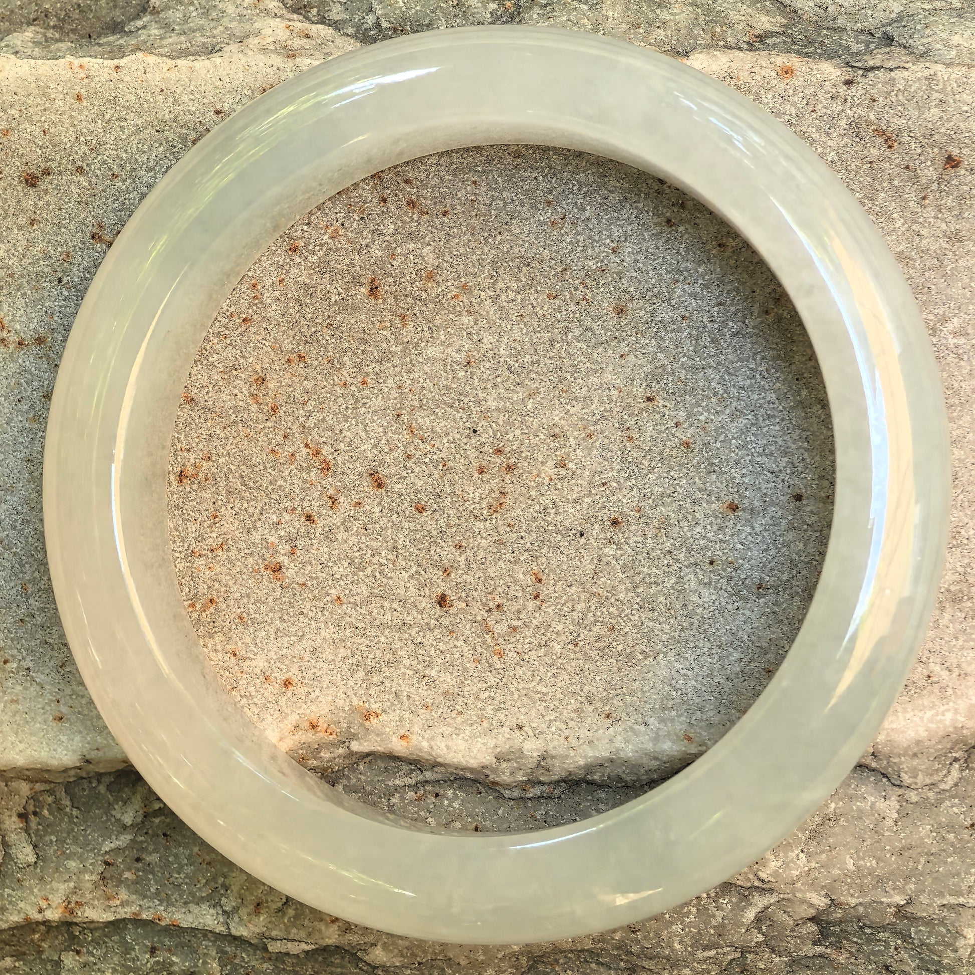 Top view of an icy white Burmese jadeite D-shape bangle showing its even circular form, soft cloud-like texture, and natural translucency.