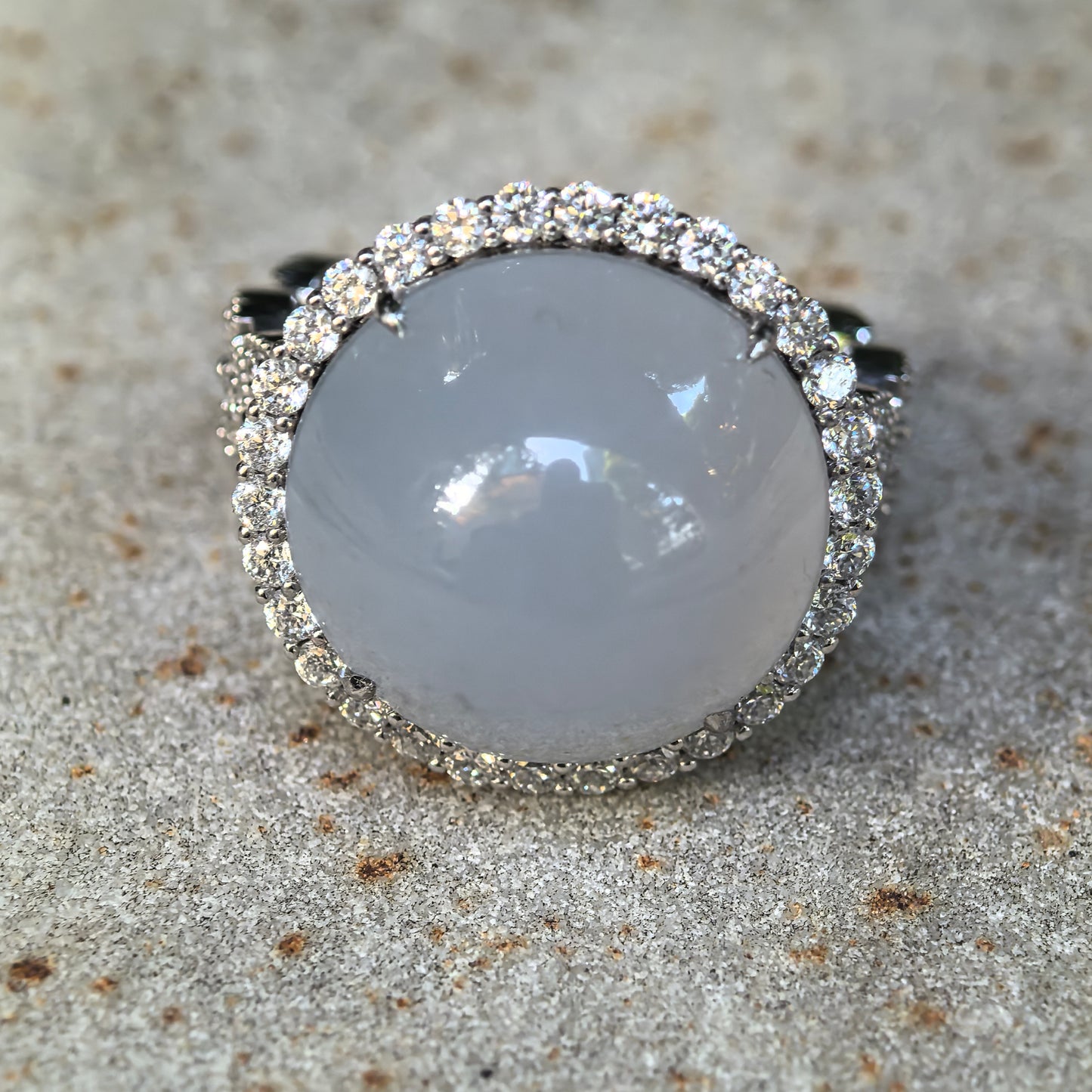 Front close-up of a large light blue Burmese jadeite cabochon ring surrounded by sparkling synthetic diamonds in Pt950 platinum.