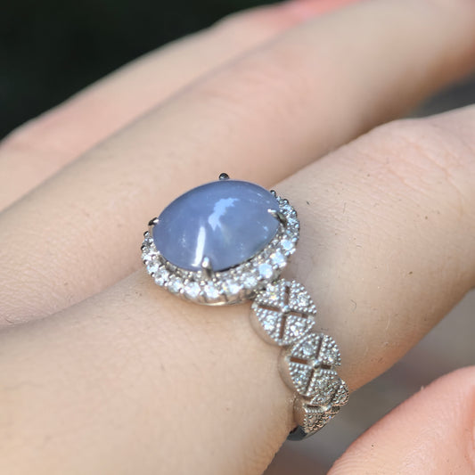 Macro wearing view of a natural Grade-A glutinous lavender-purple jadeite cabochon ring with a sparkling synthetic diamond halo.