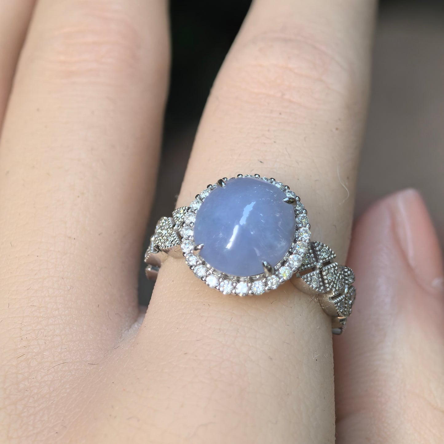 Front close-up of a rich lavender Burmese jadeite oval cabochon set in Pt950 platinum with synthetic diamond floral shoulders.