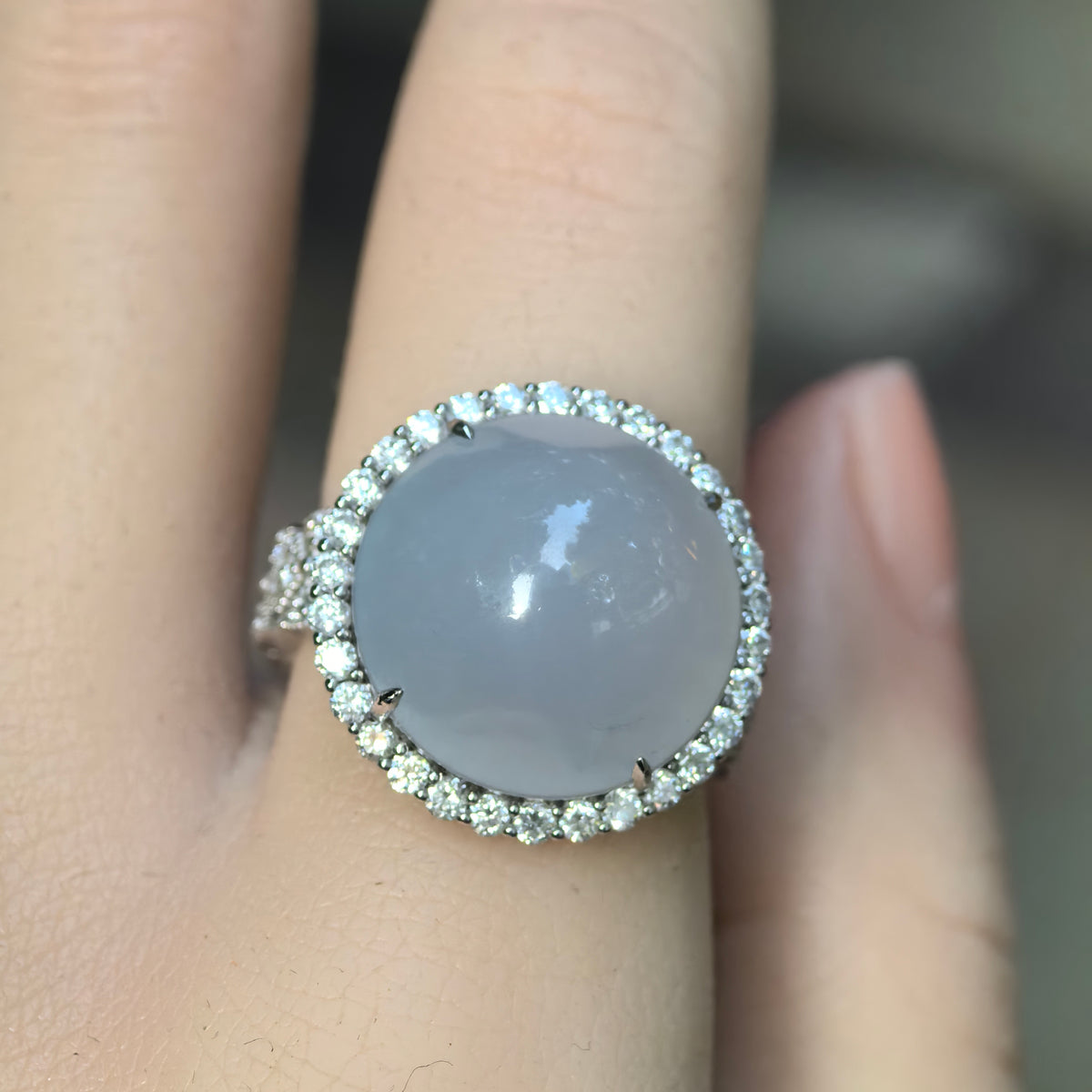 Front wearing view of a natural Grade-A icy glutinous light blue jadeite ring with a large round cabochon and sparkling halo setting.