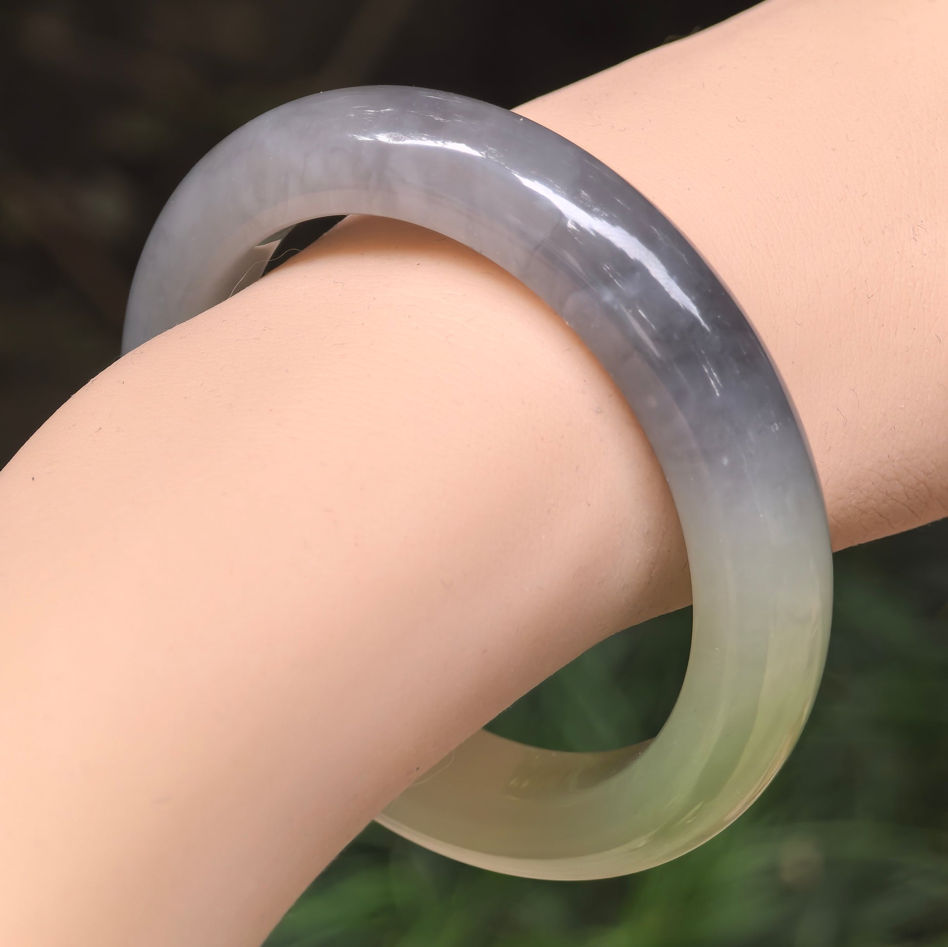 Close-up wrist view of a natural smoky purple Hetian jade D-shape bangle with a smooth oily luster.