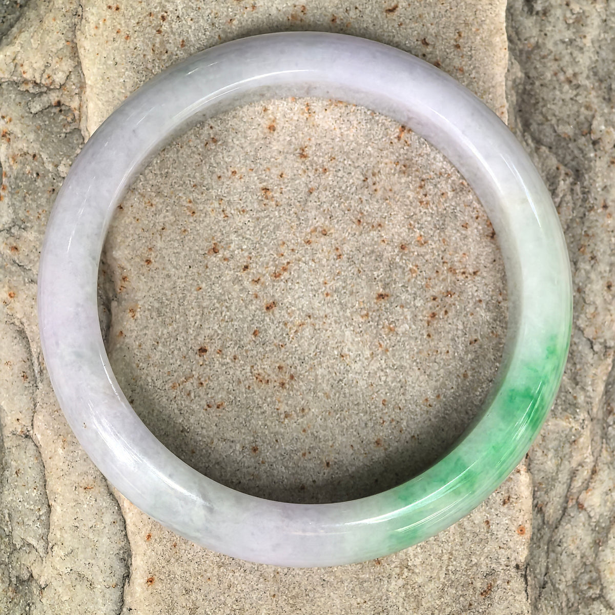 Full view of a glutinous lavender-green Burmese jadeite D-shape bangle showing its broad polished profile and natural color transition.