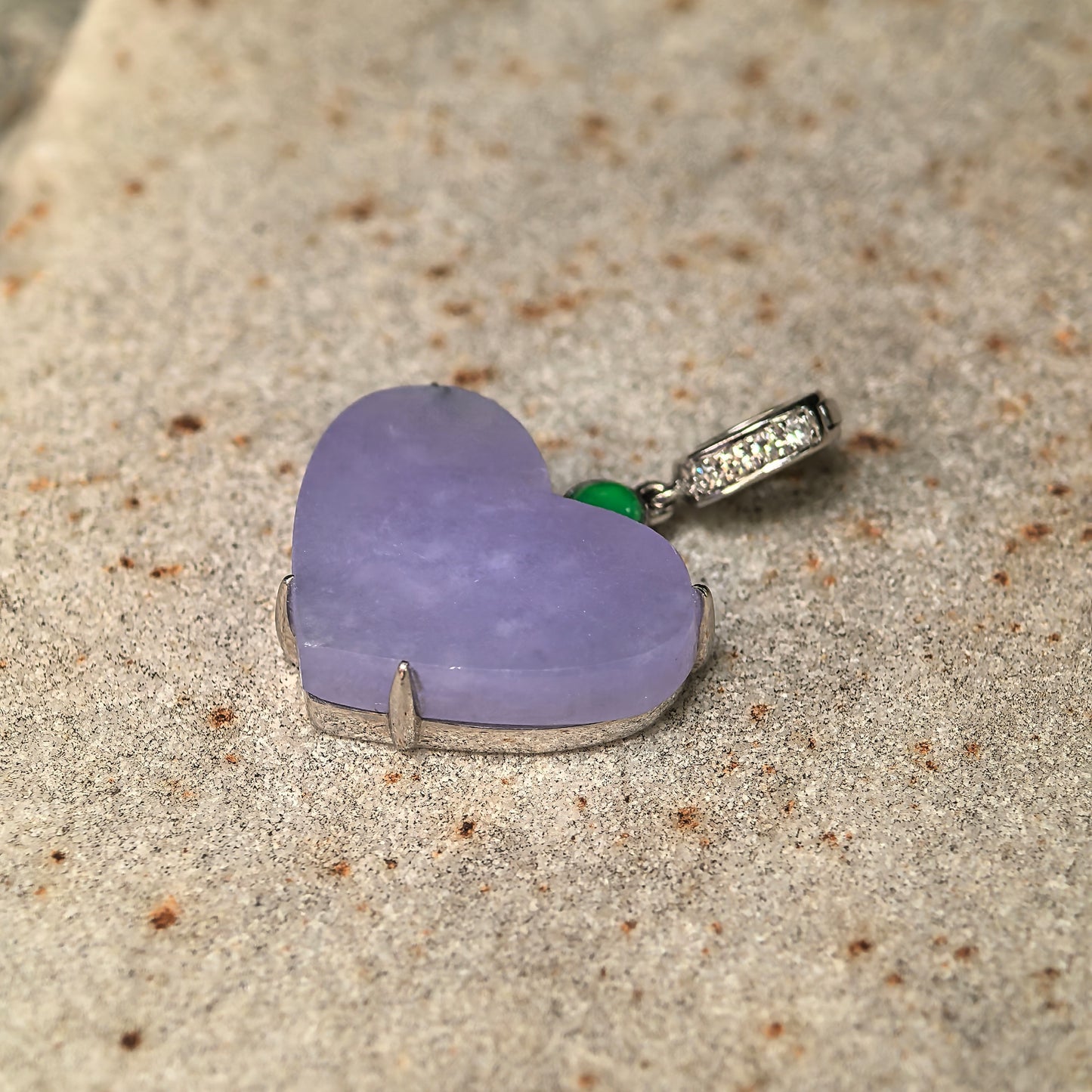 Side view of heart-shaped lavender jadeite pendant showing 18K gold mounting and diamond accents.