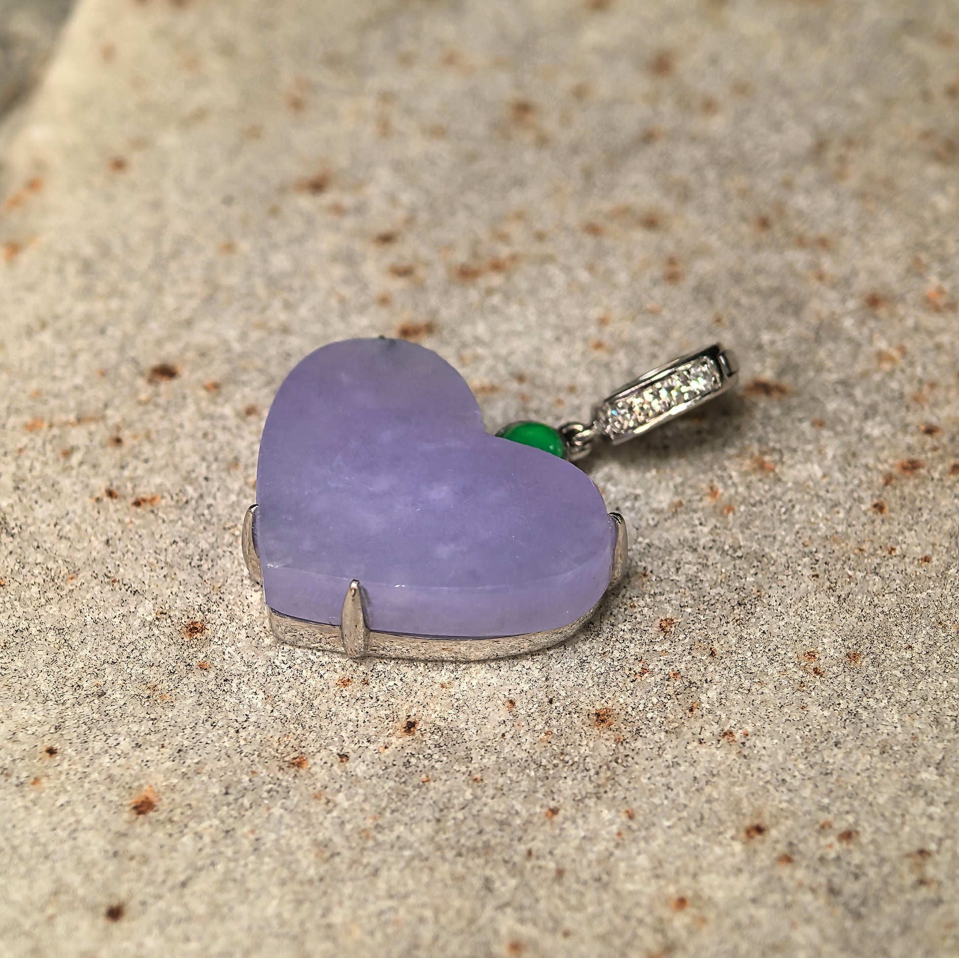 Side view of heart-shaped lavender jadeite pendant showing 18K gold mounting and diamond accents.