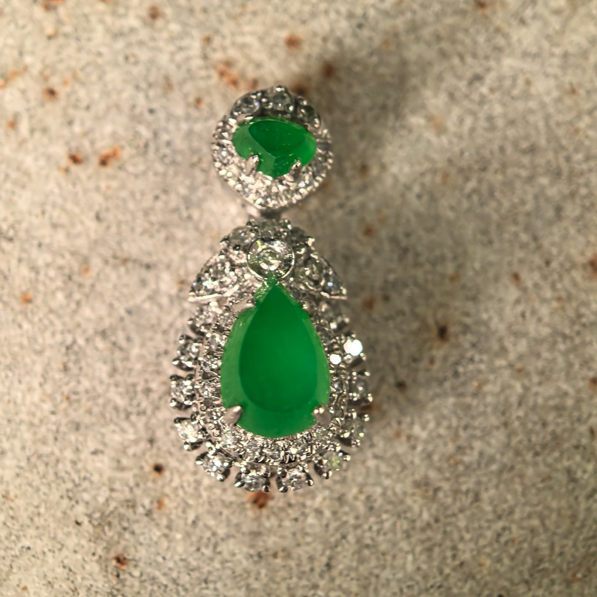 Close-up front view of bright green icy jadeite teardrop pendant showing vivid color, clean translucency, and diamond setting.