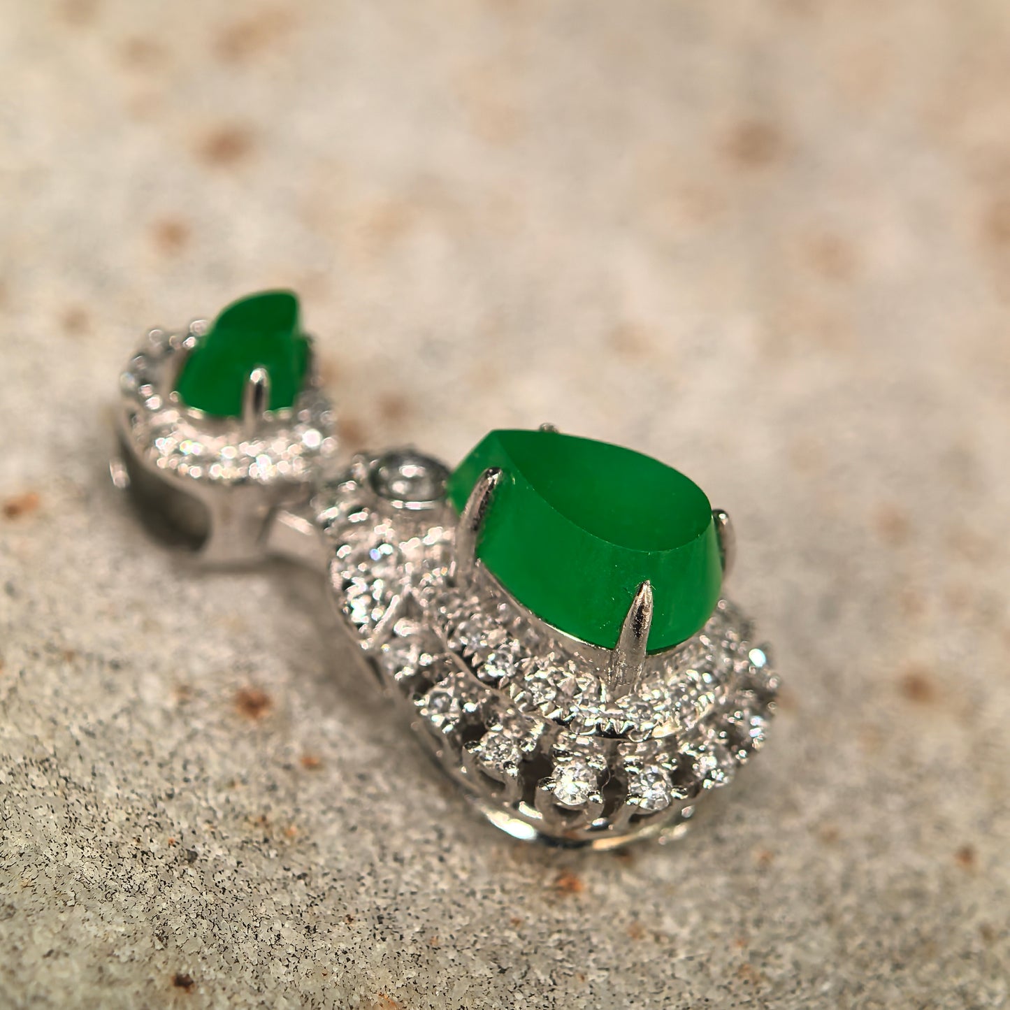 Natural Grade-A icy bright green teardrop jadeite pendant in 18K gold with diamond accents shown from a side angle.