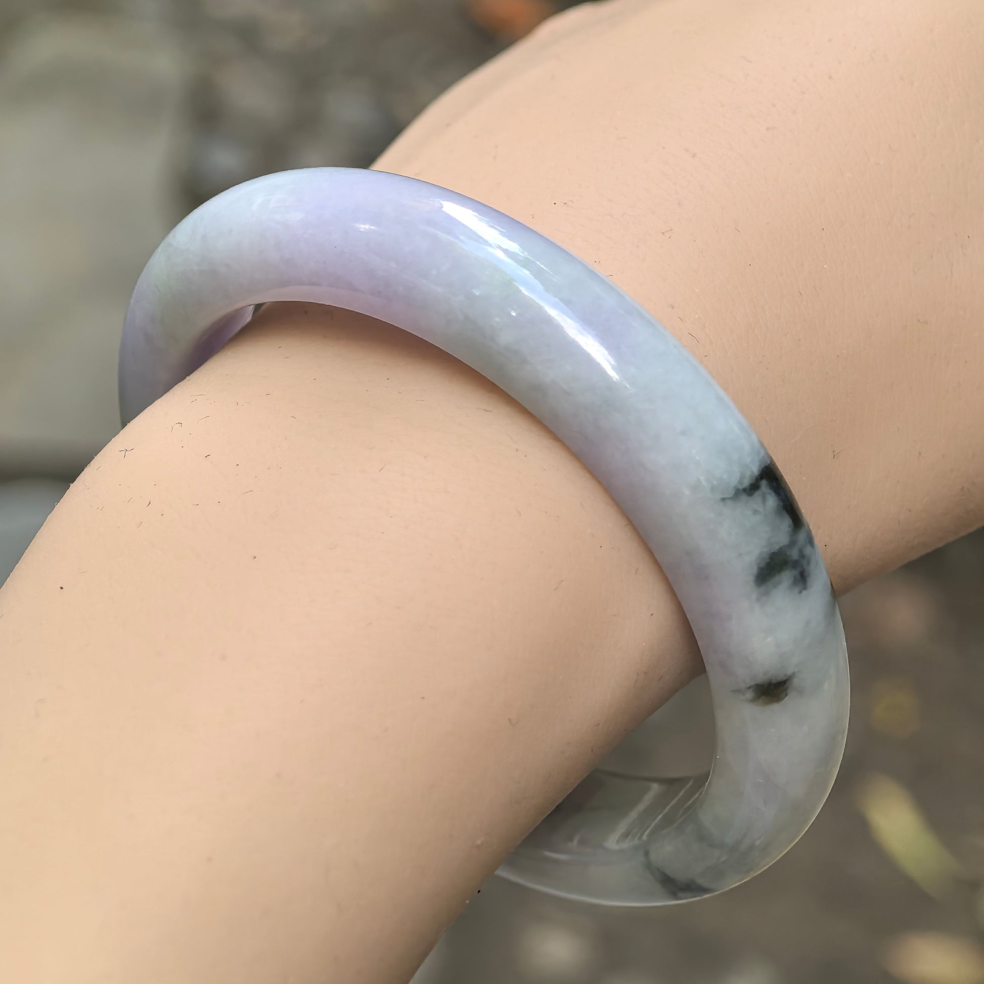 Natural Grade-A glutinous pale lavender jadeite D-shape bangle with dark green floating flower worn on the wrist.