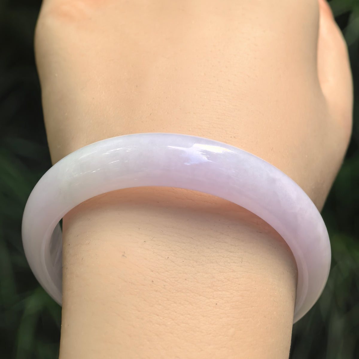 Lavender Burmese jadeite D-shape bangle worn on the wrist, showing smooth polish, gentle translucency, and subtle pale green tones.