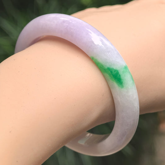 Natural Grade-A glutinous pale lavender jadeite D-shape bangle worn on the wrist, showing its concentrated bright green section.