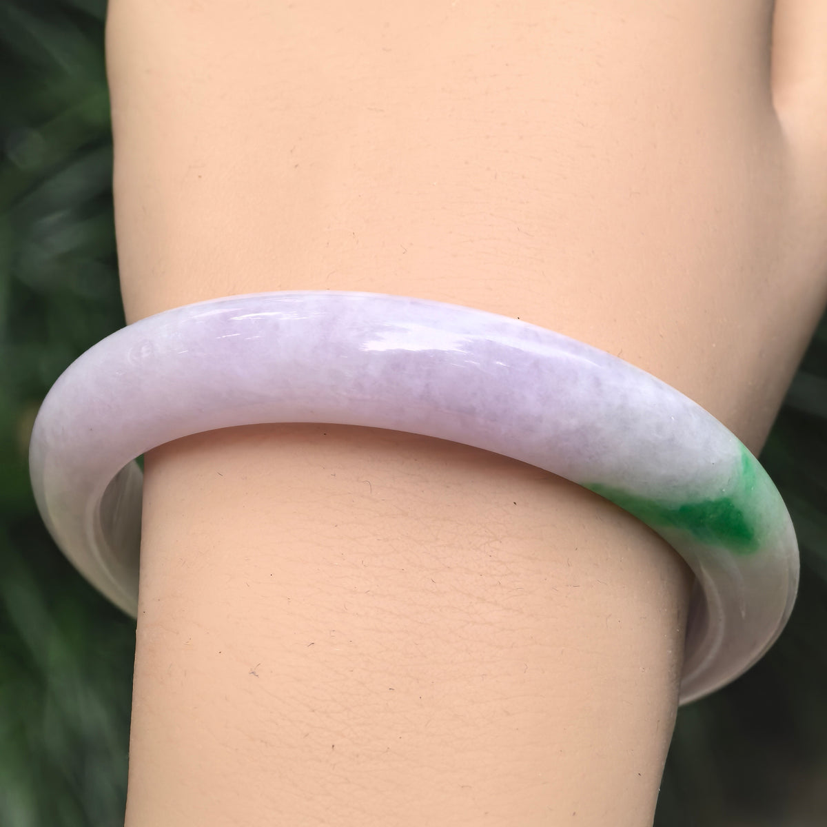 Wrist view of pale lavender Burmese jadeite bangle with vivid green accent and smooth glutinous texture.