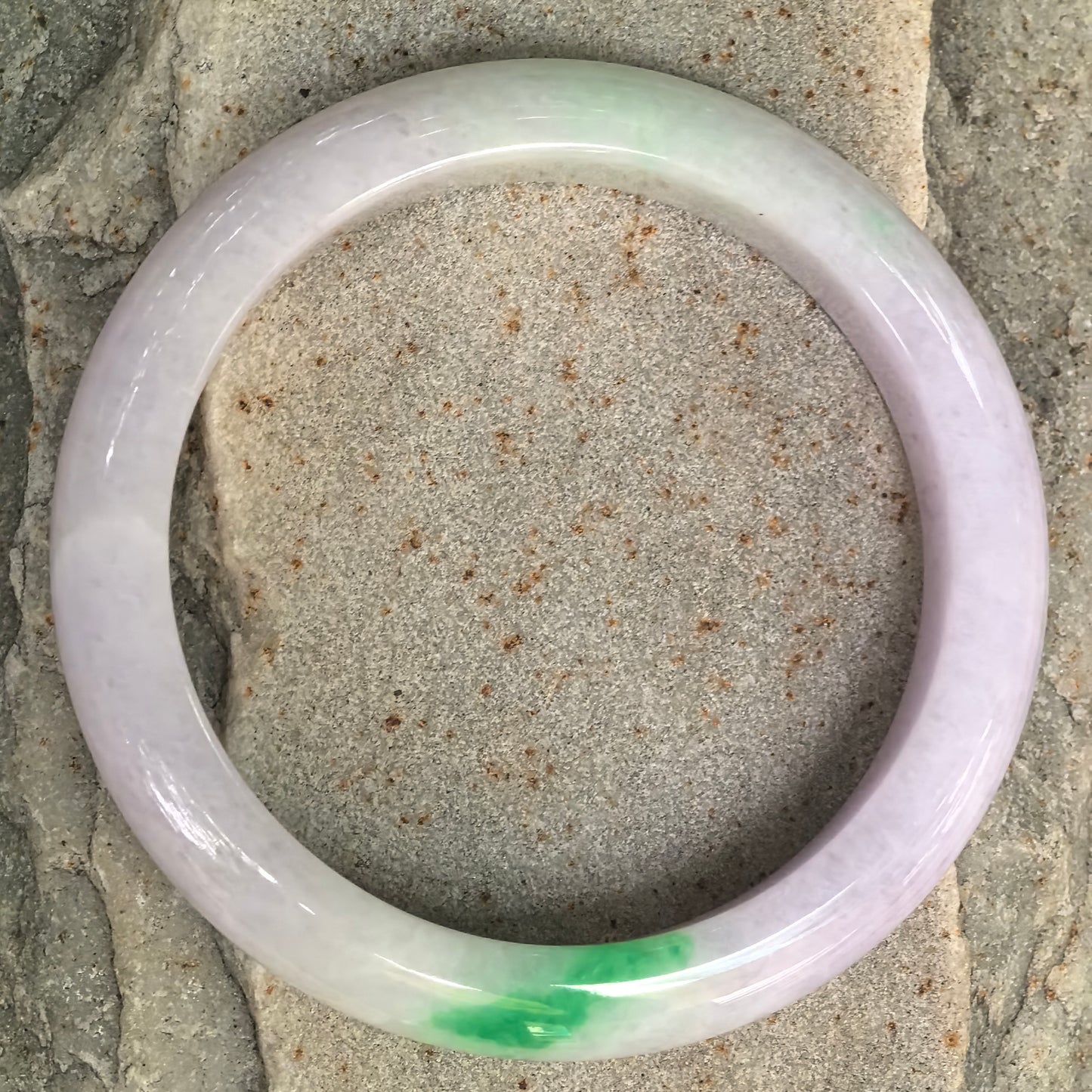 Top view of glutinous lavender jadeite bangle showing its bright green section and classic D-shape structure.