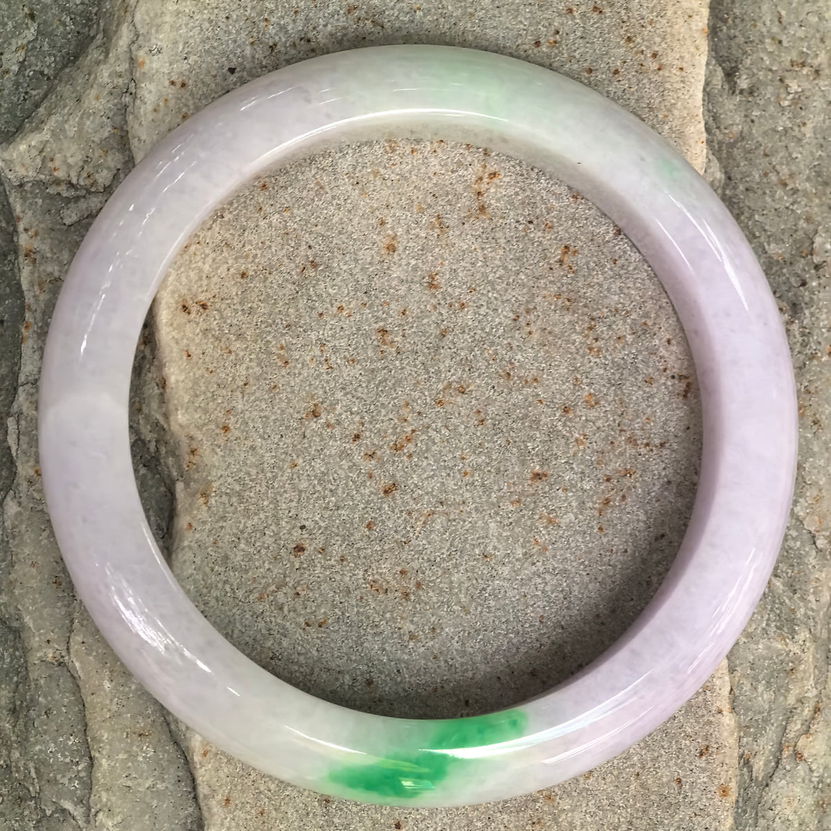 Top view of glutinous lavender jadeite bangle showing its bright green section and classic D-shape structure.