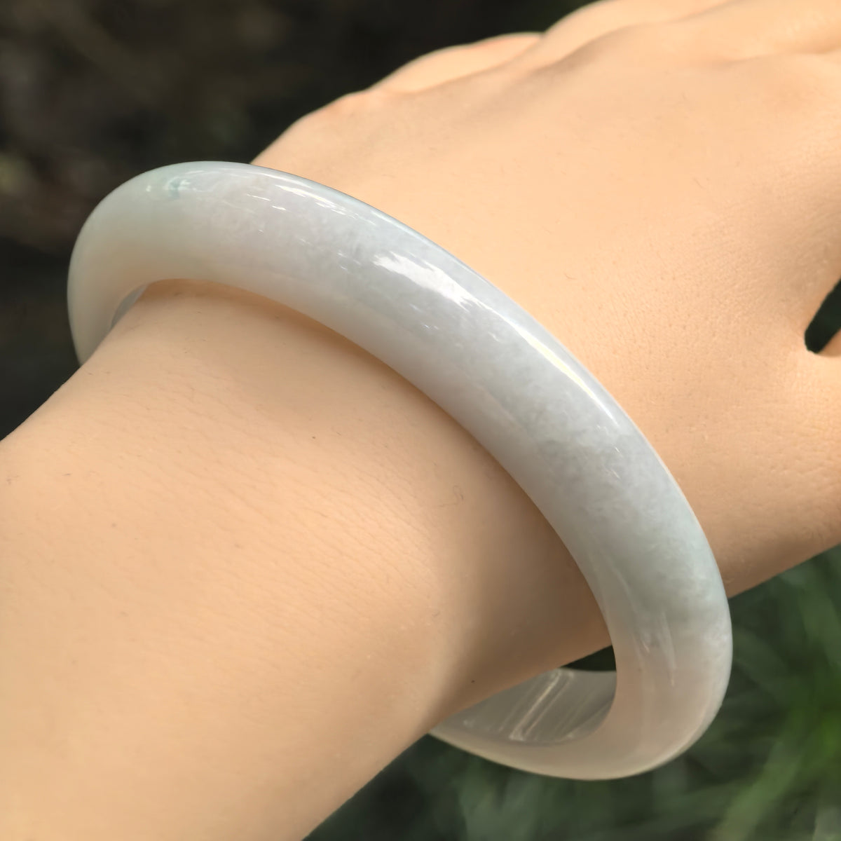 Natural Grade-A pale blue glutinous jadeite bangle worn on the wrist showing its broad D-shape profile.