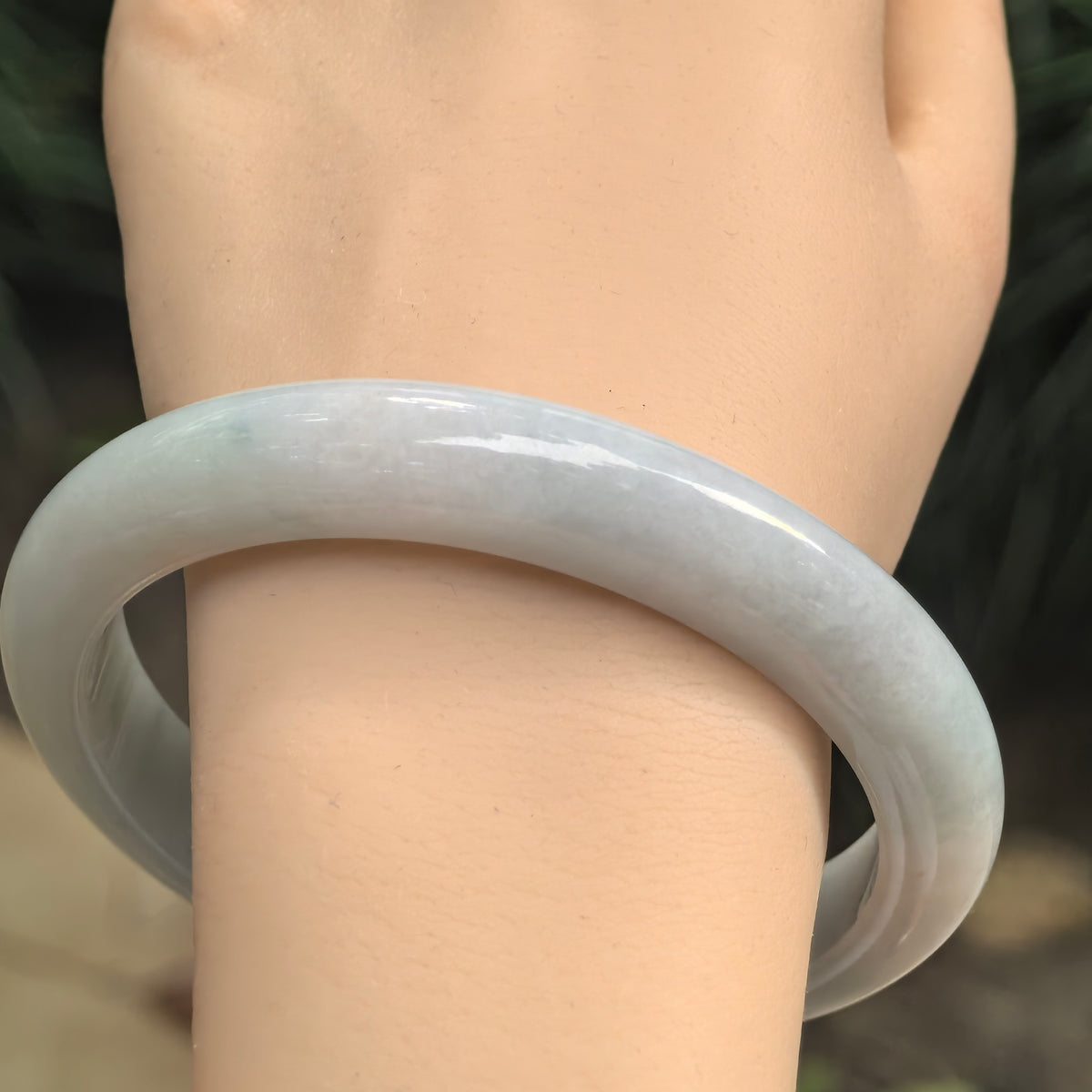 Large-size pale blue Burmese jadeite bangle worn on the wrist with smooth luster and clean natural texture.