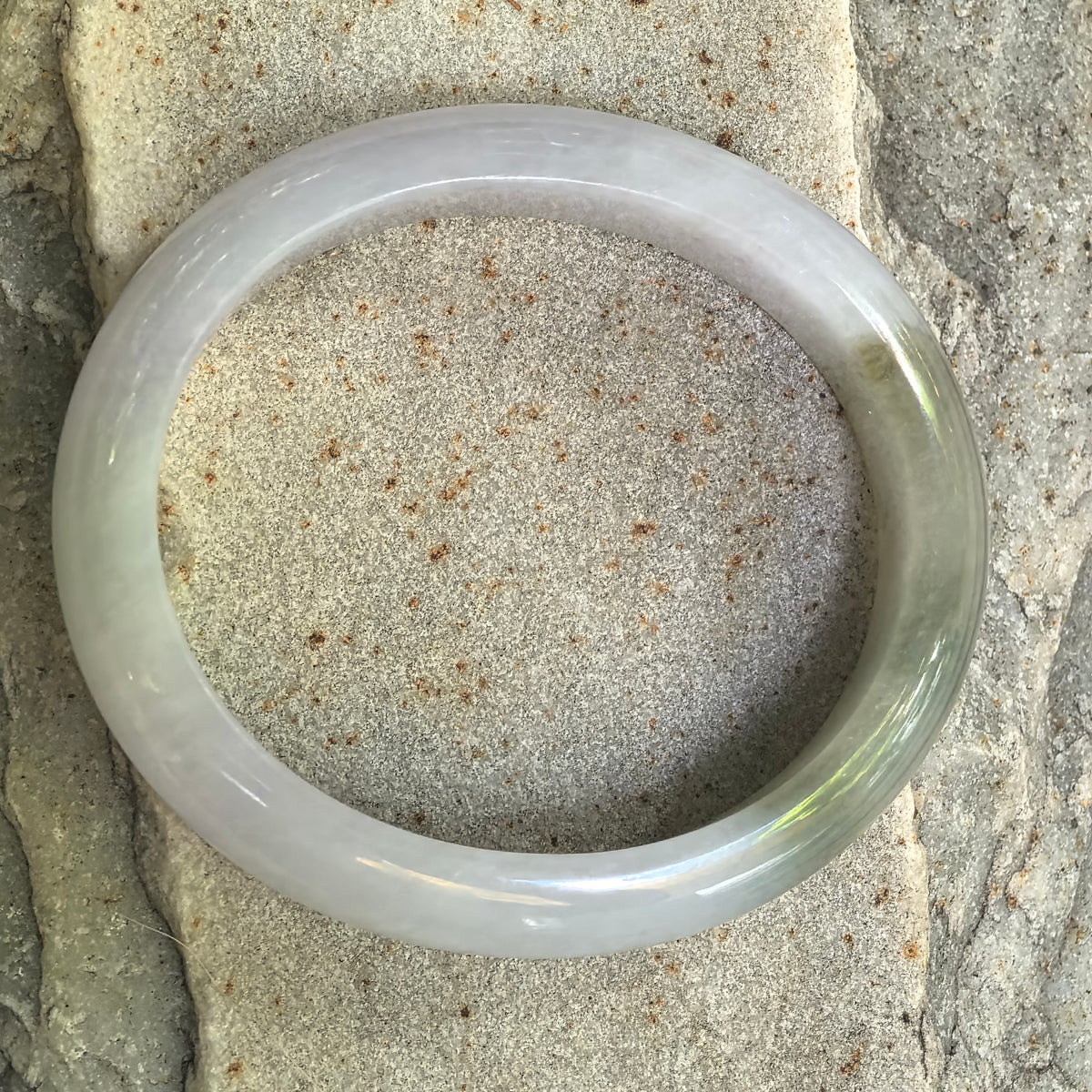 Top view of pale lavender and oil green Burmese jadeite oval bangle showing its elongated inner opening and natural color transition.