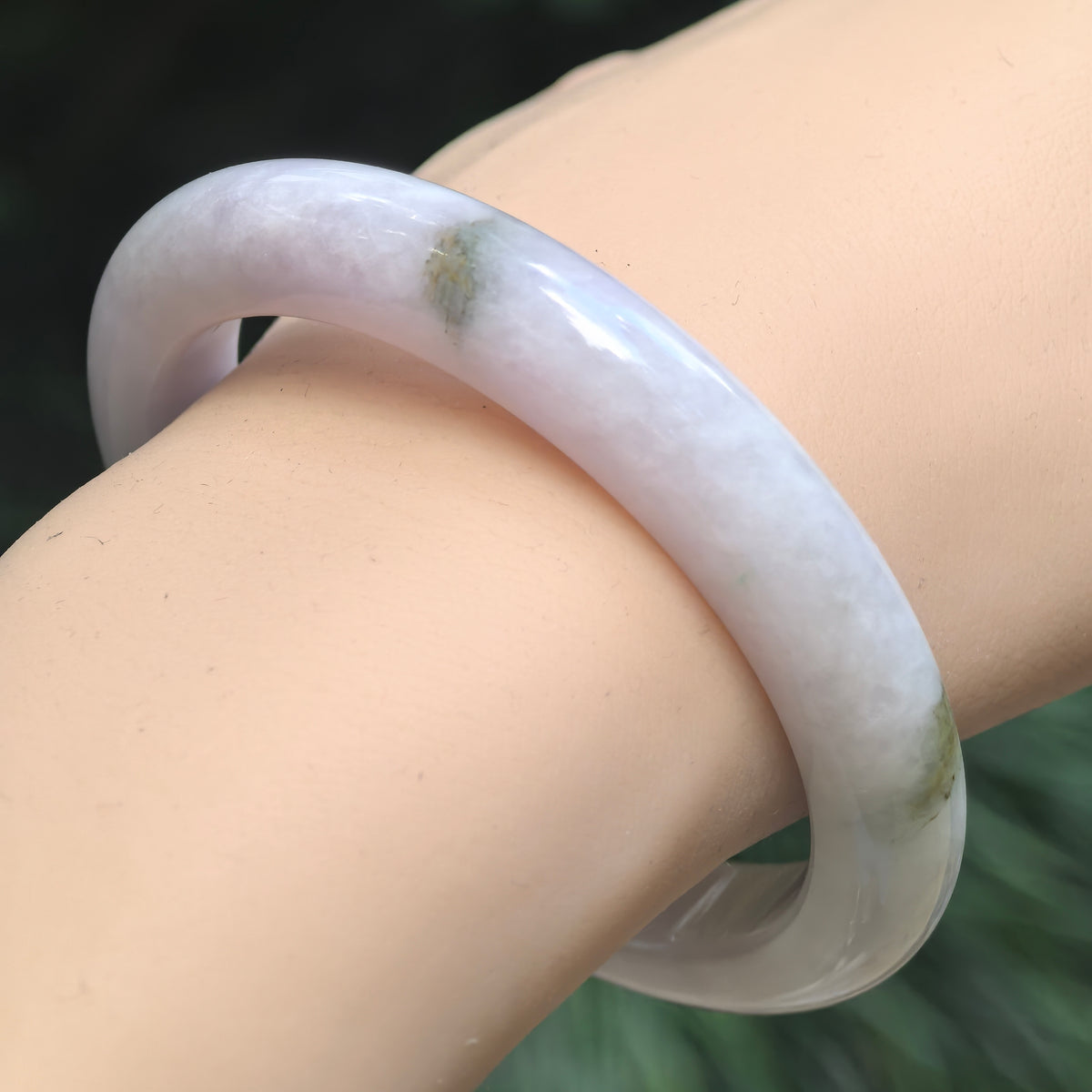 Natural Grade-A pale lavender jadeite bangle worn on the wrist, showing the polished D-shape profile and natural color variation.