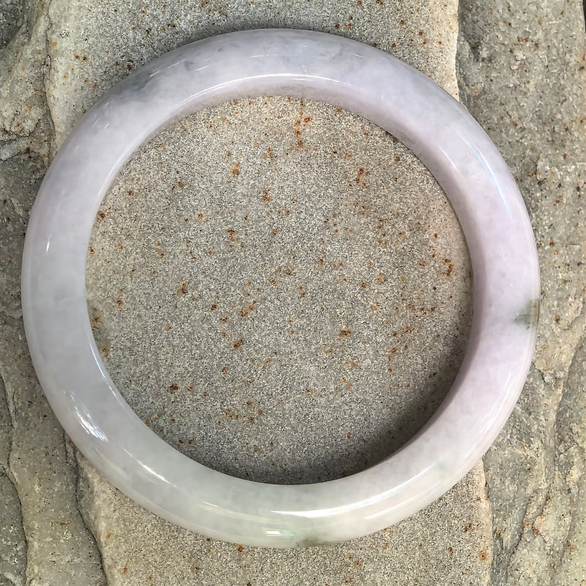 Top view of pale lavender Burmese jadeite bangle showing its glutinous texture and natural dark green floating flower.