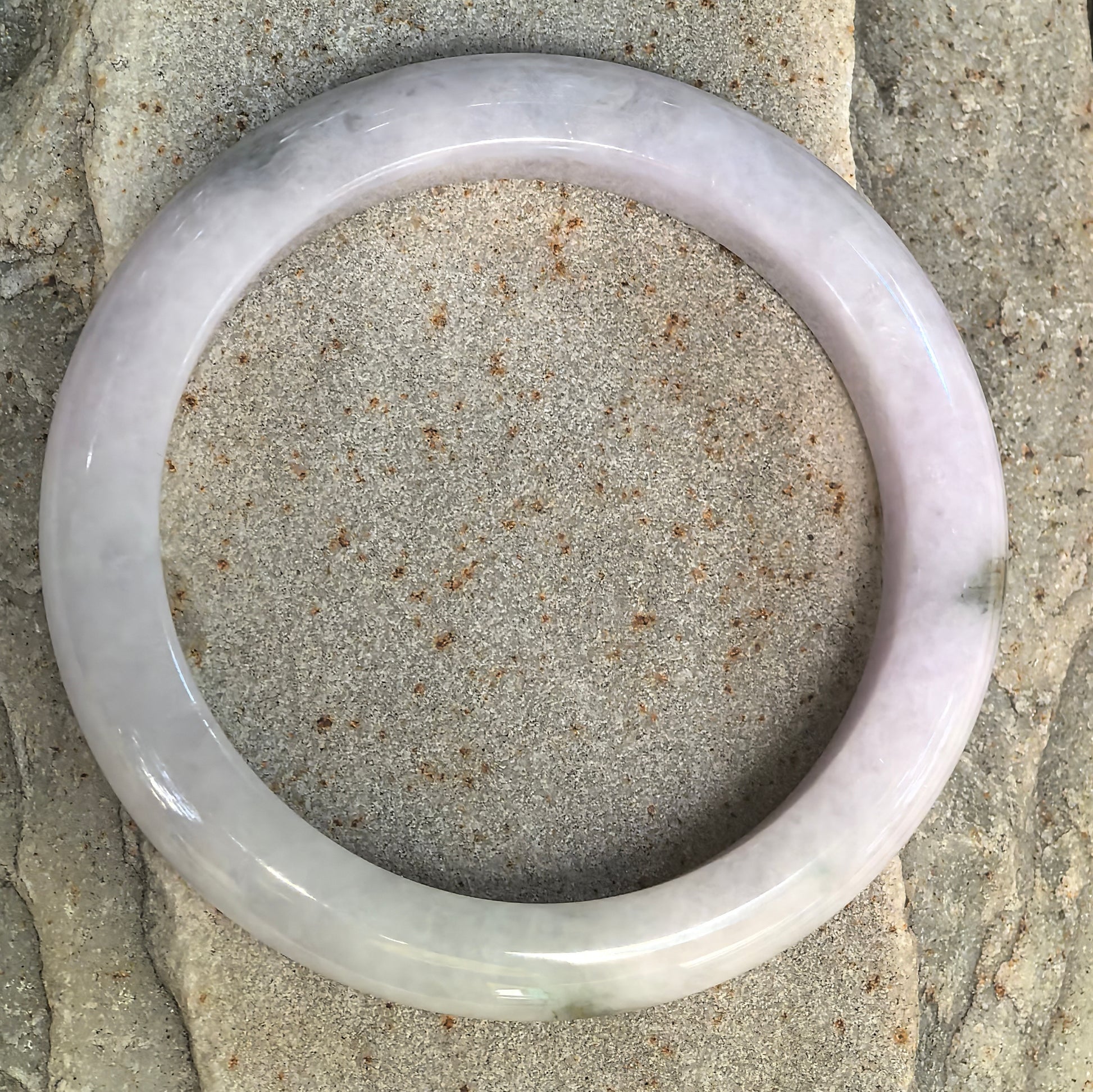 Top view of pale lavender Burmese jadeite bangle showing its glutinous texture and natural dark green floating flower.