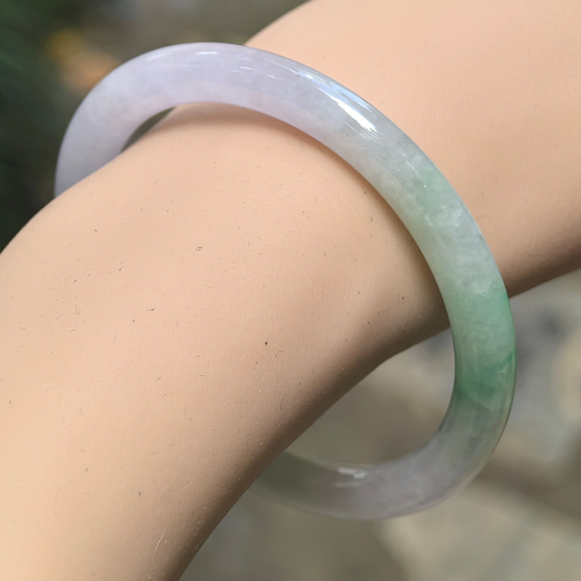 Natural Grade-A icy glutinous pale lavender and green round jadeite bangle worn on the wrist, showing its slim profile and translucent color.