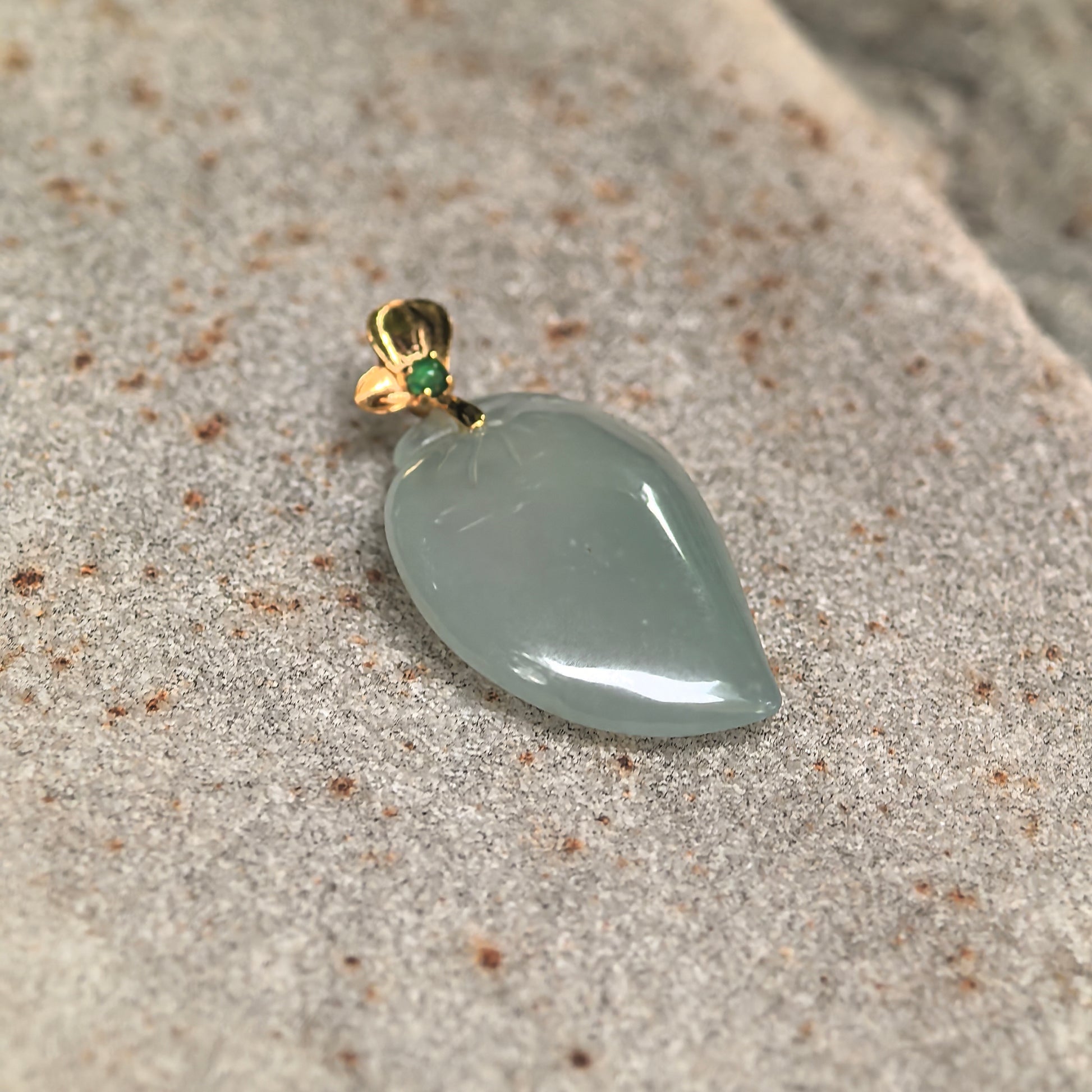 Close-up of Natural Grade-A light green peach jadeite pendant showing its smooth polished surface and carved peach details.