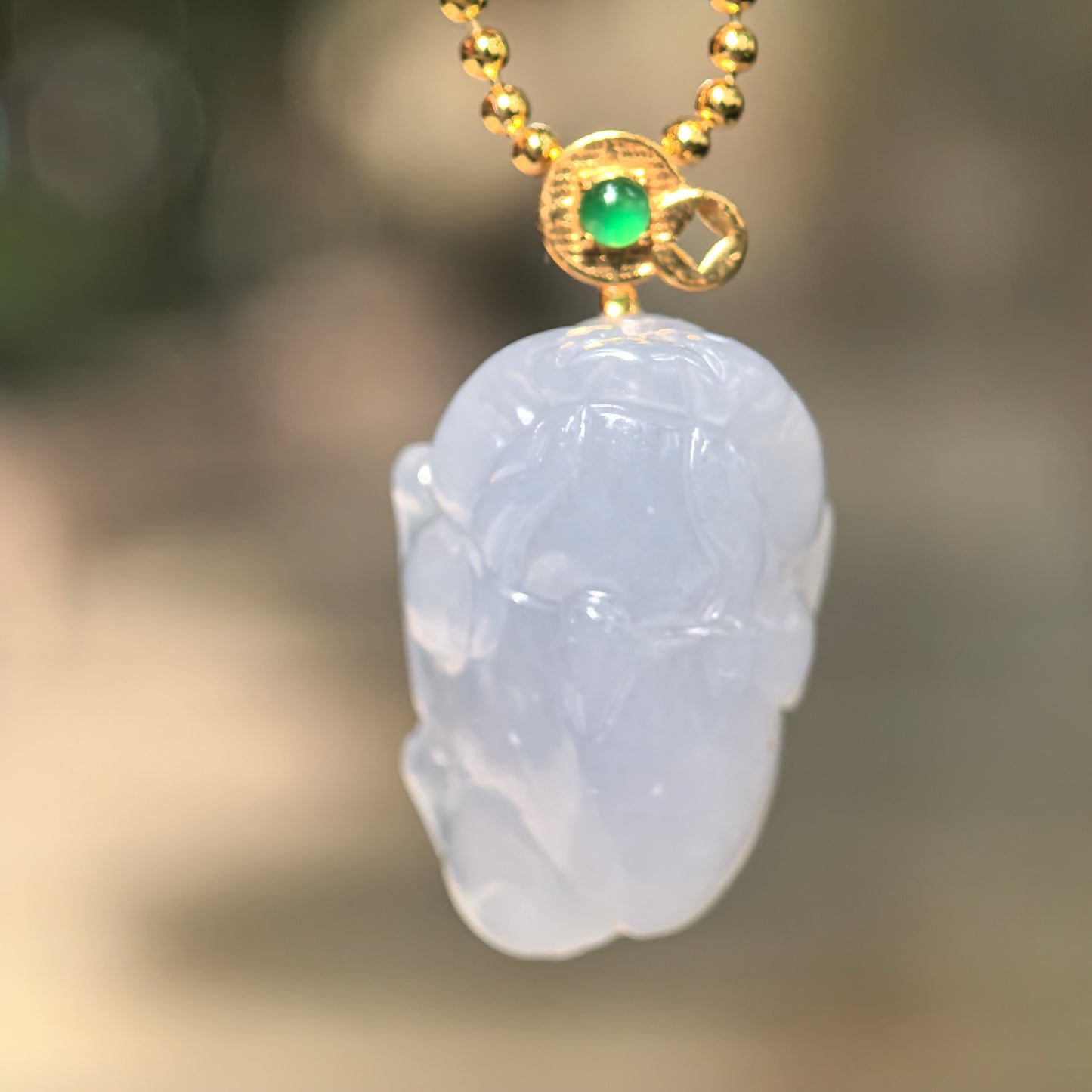 Natural Grade-A icy glutinous lavender Money Toad jadeite pendant hanging from a chain with an 18K gold bail and green accent stone.