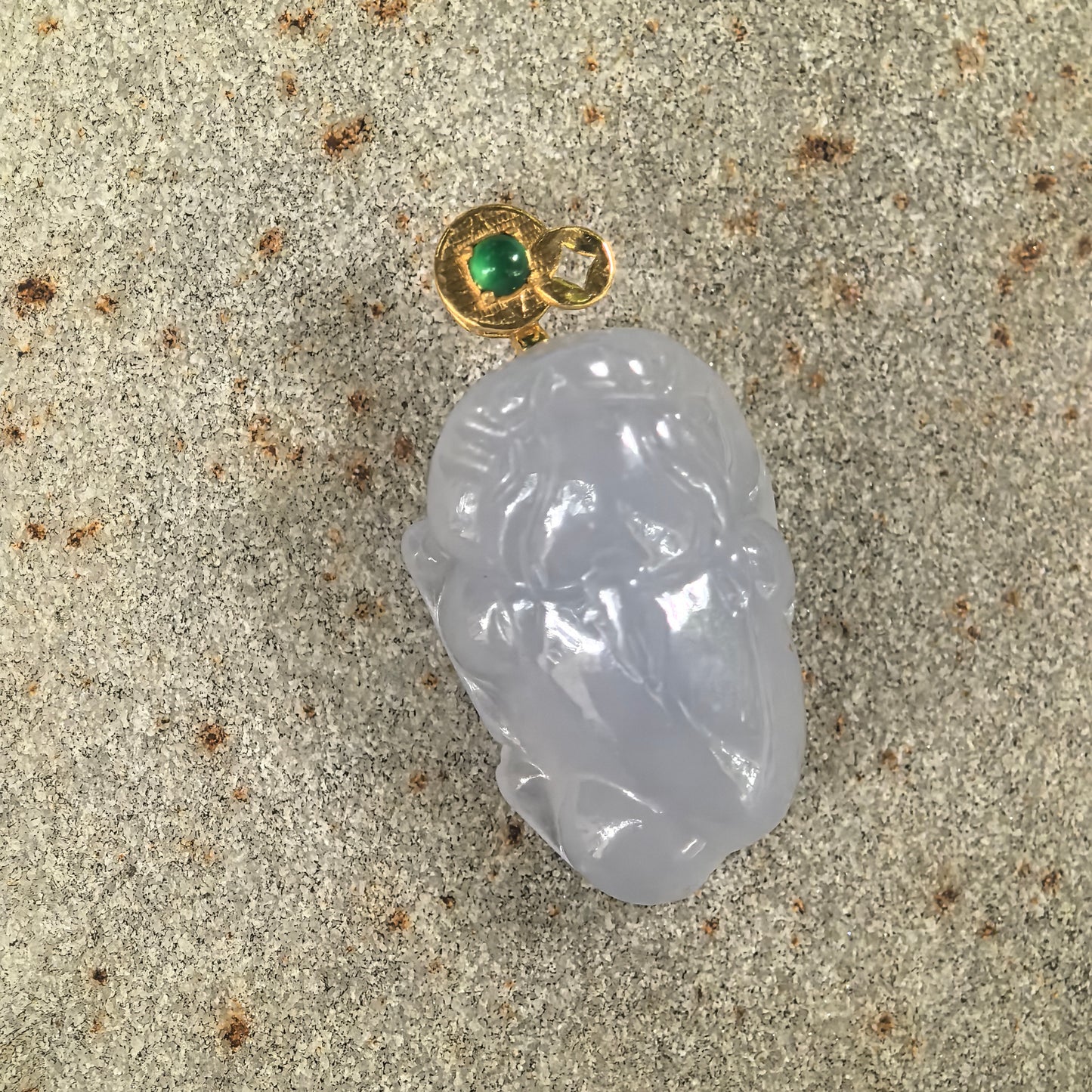 Natural Grade-A lavender jadeite Money Toad pendant displayed on stone with an 18K gold bail and green accent stone.