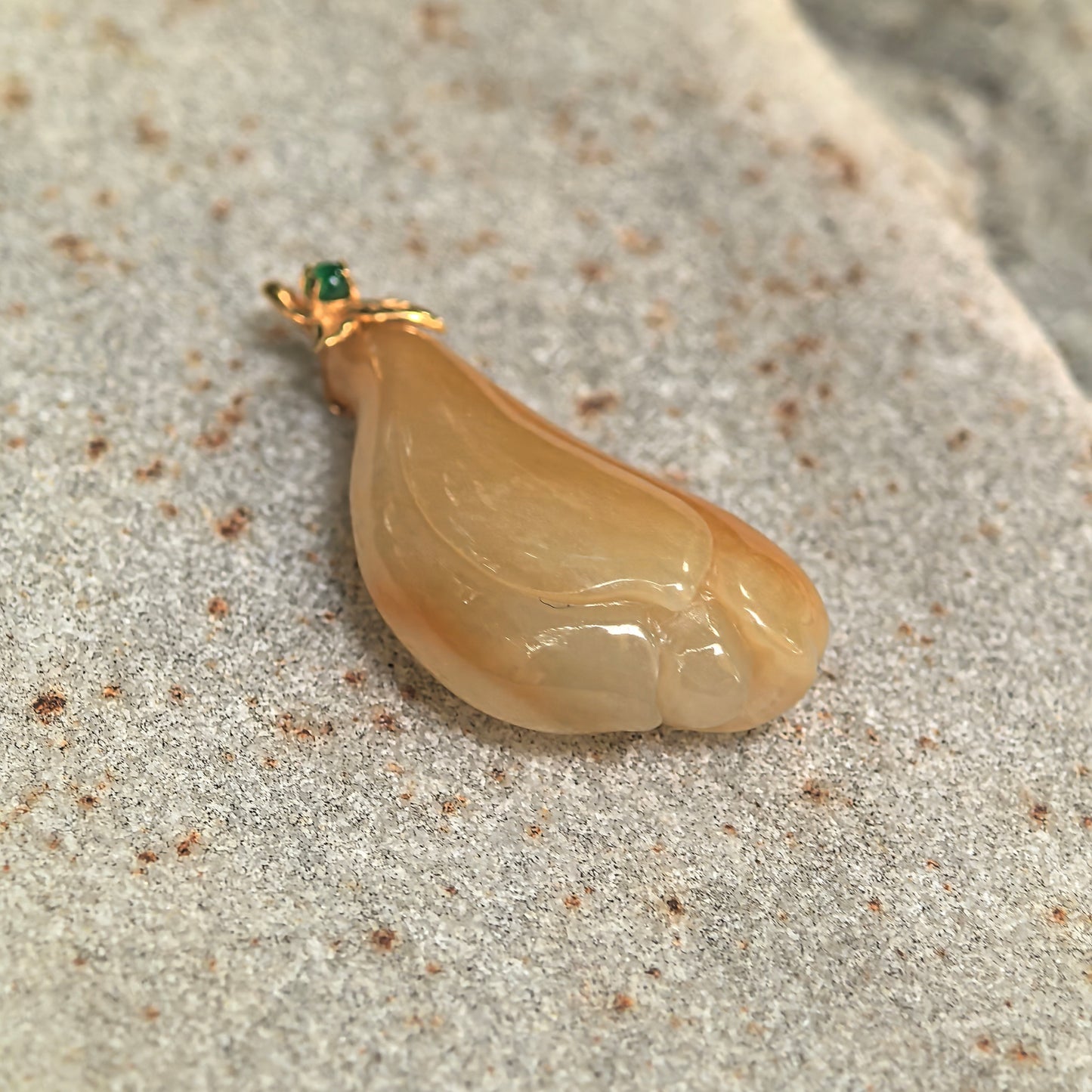 Close-up of icy glutinous yellow magnolia jadeite pendant showing its polished layered petal carving and warm golden tone.