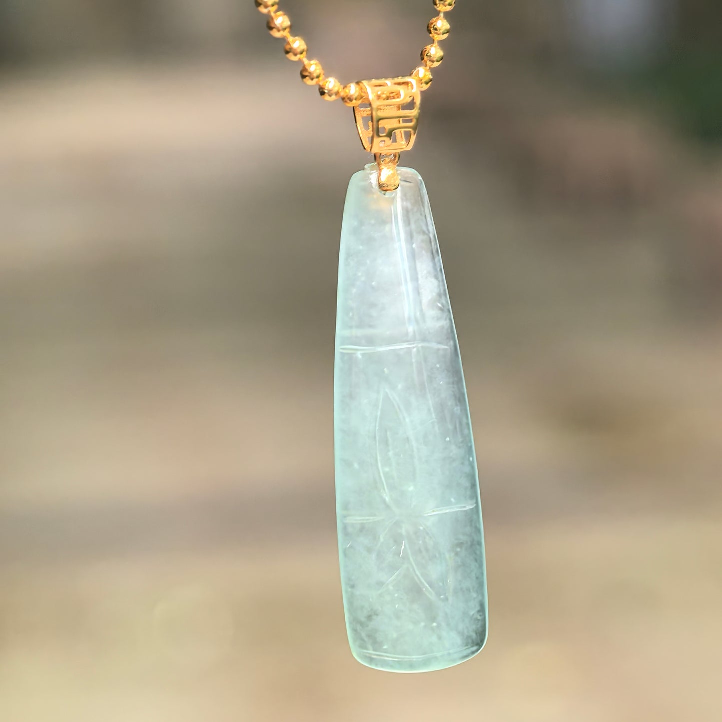 Natural Grade-A icy light green bamboo jadeite pendant hanging from a chain, showing its slender carved bamboo segment design.