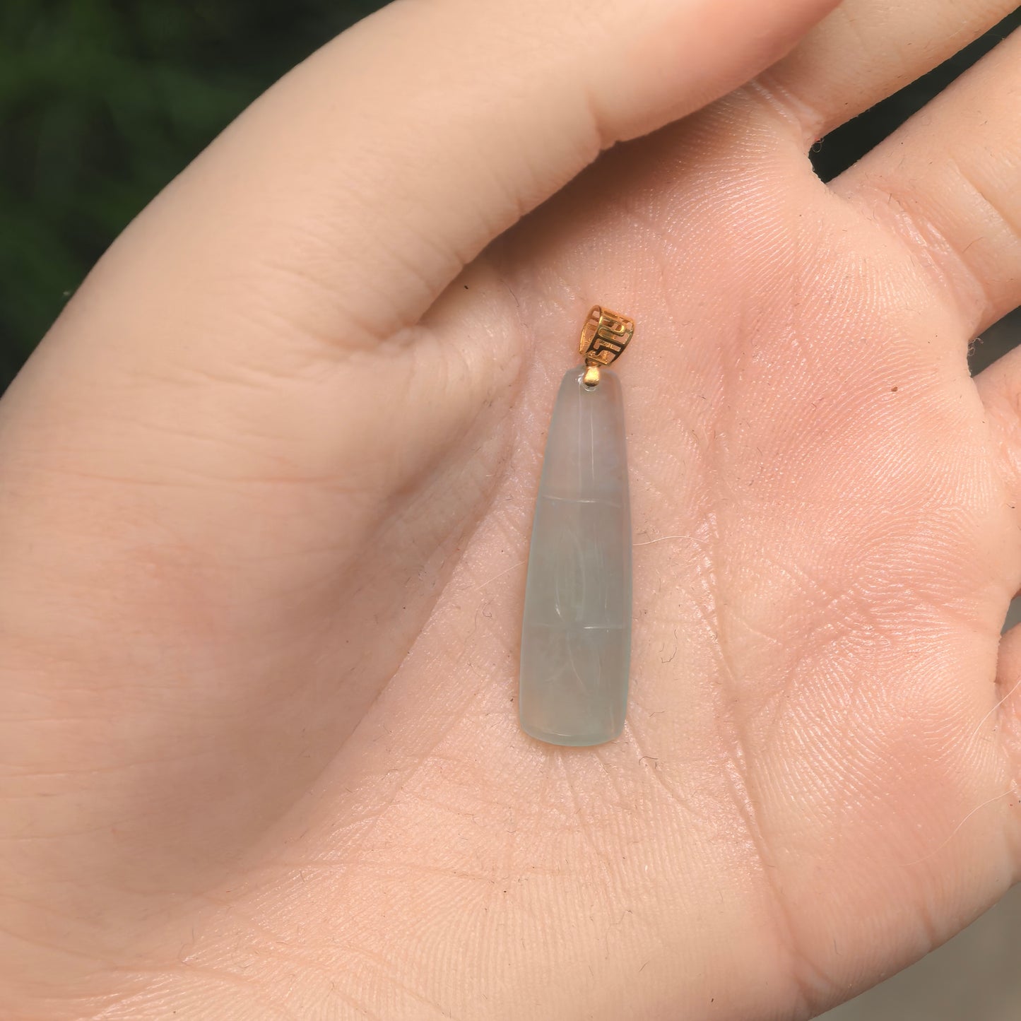 Icy light green bamboo jadeite pendant with 18K gold bail shown in hand for scale.