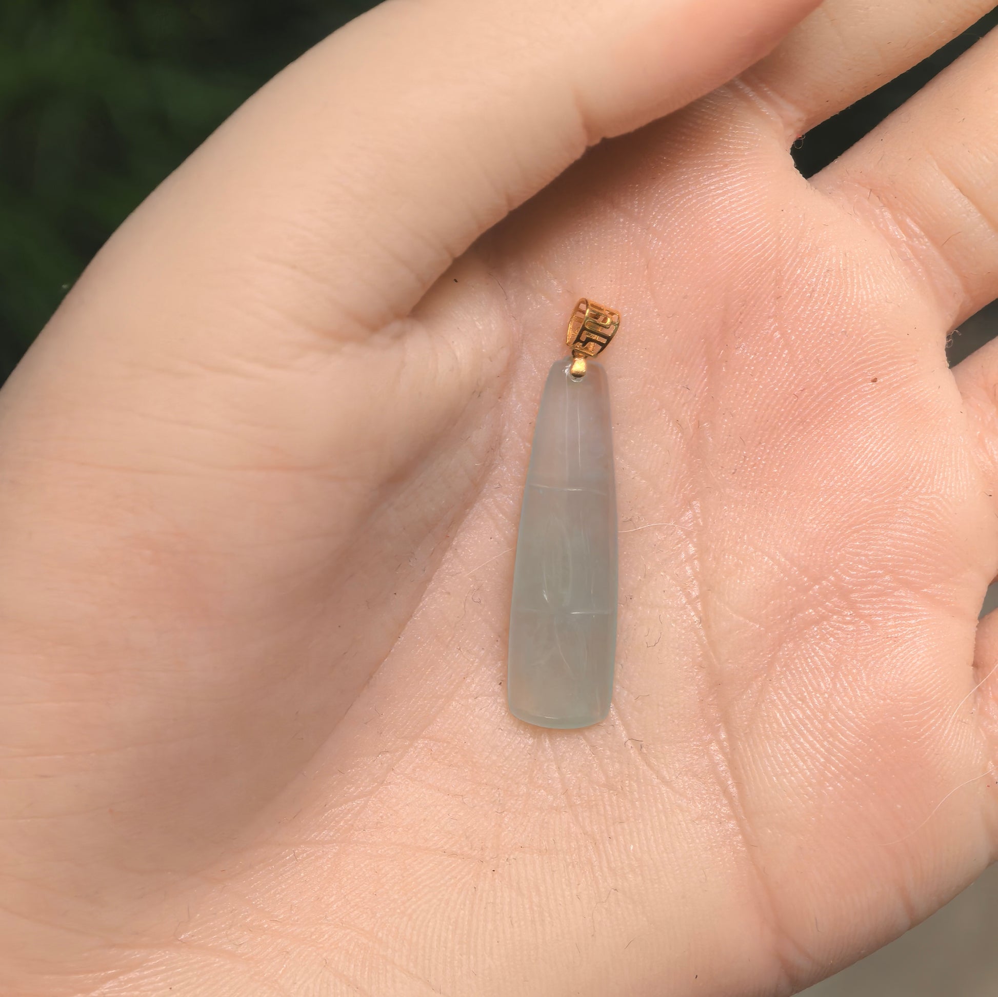 Icy light green bamboo jadeite pendant with 18K gold bail shown in hand for scale.