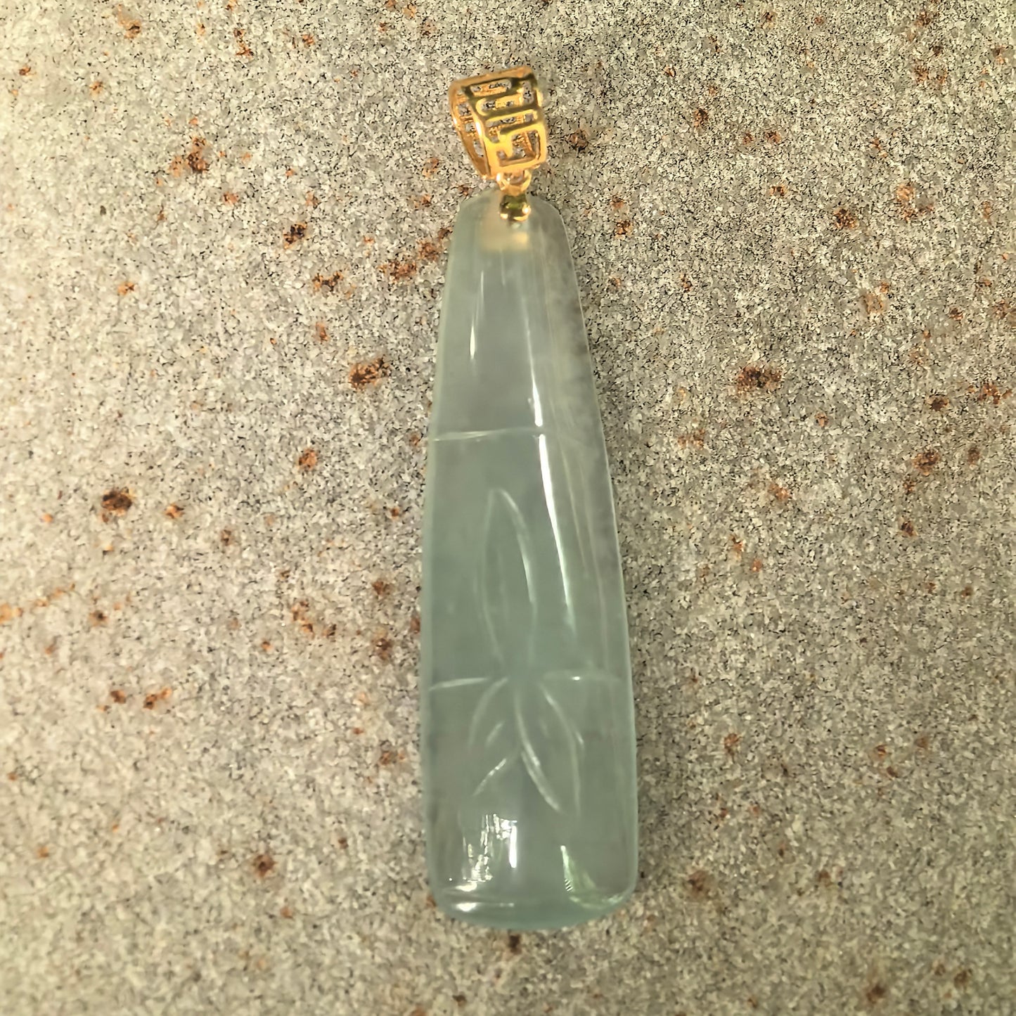Natural Grade-A icy light green bamboo jadeite pendant showing the elongated bamboo segment carving and 18K gold bail.