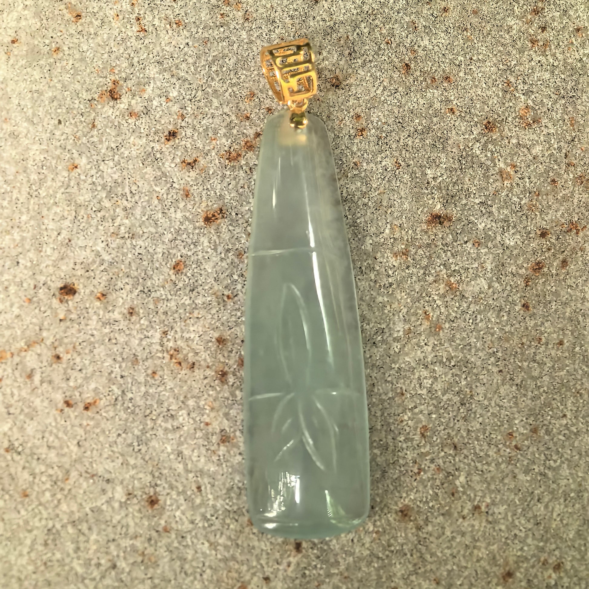 Natural Grade-A icy light green bamboo jadeite pendant showing the elongated bamboo segment carving and 18K gold bail.